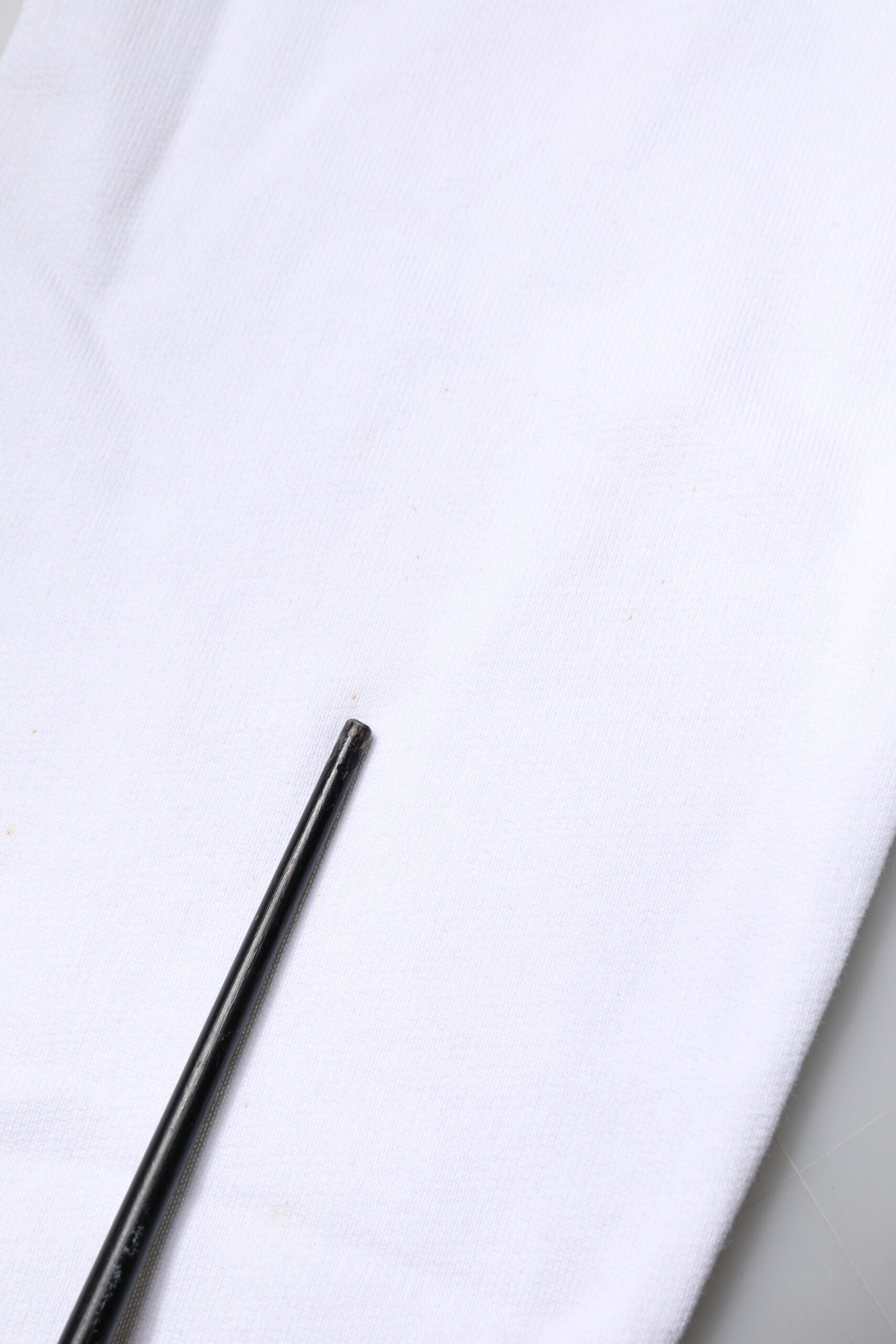Black sewing needle on white fabric