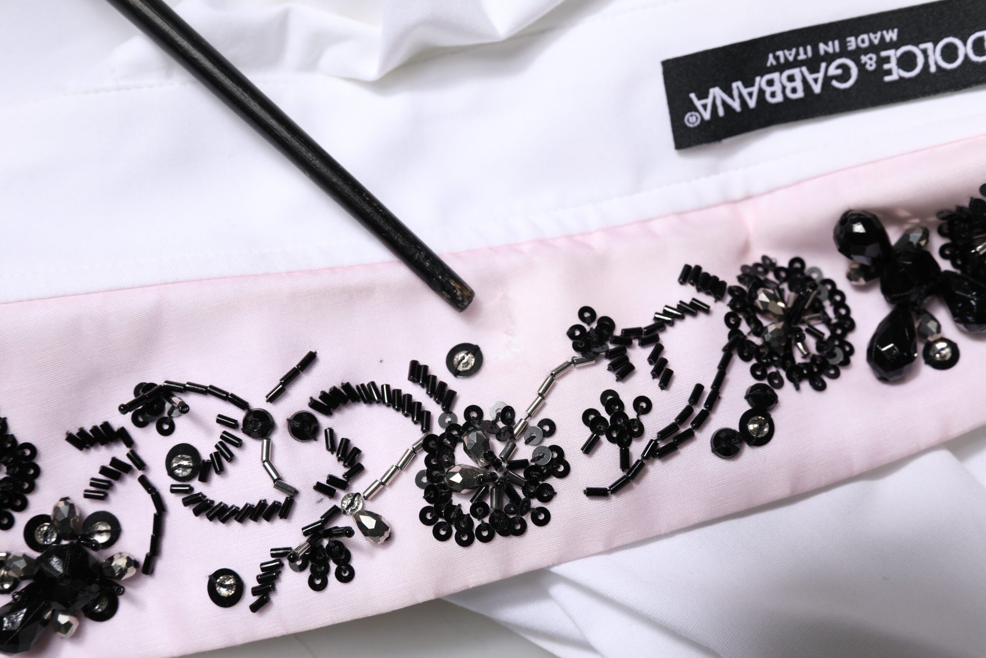 A white dress shirt with black embellishments and a pink satin ribbon