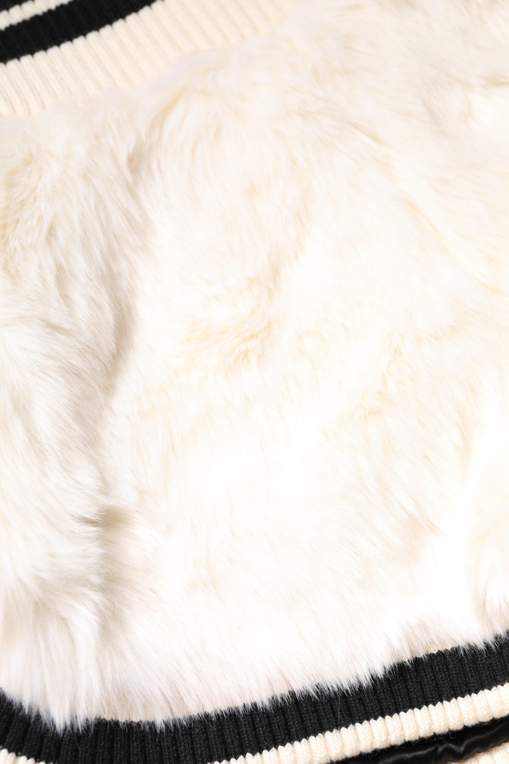Furry white sweater on striped fabric