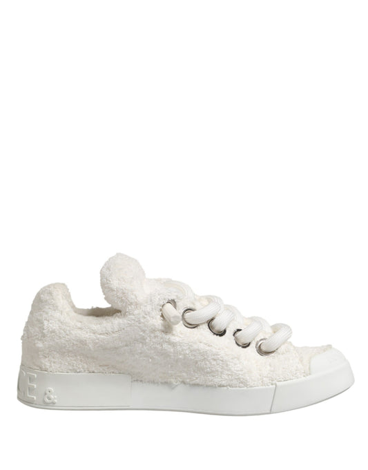 A pair of white faux shearling low top sneakers with a bow on the side
