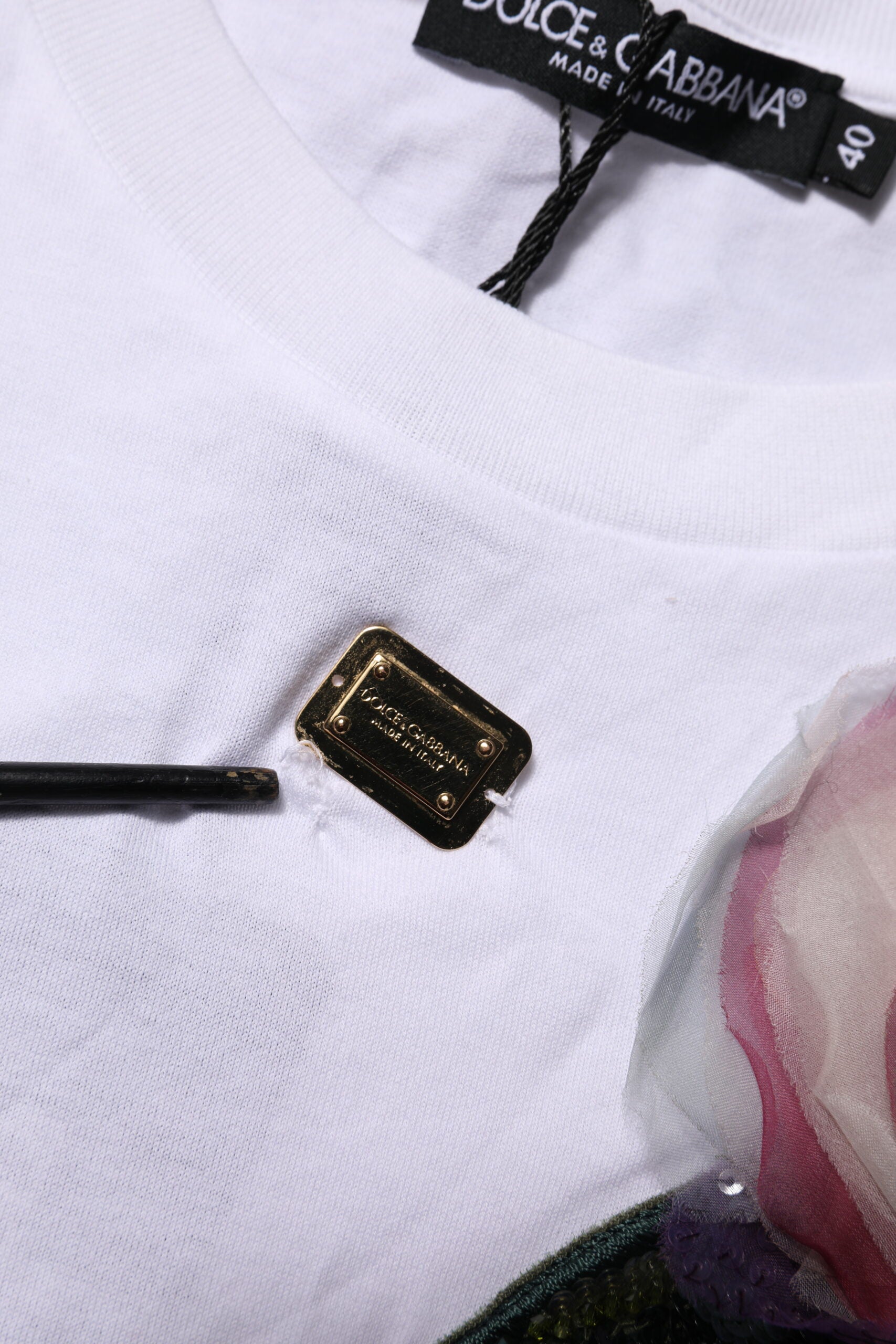White t-shirt with gold logo pin on front