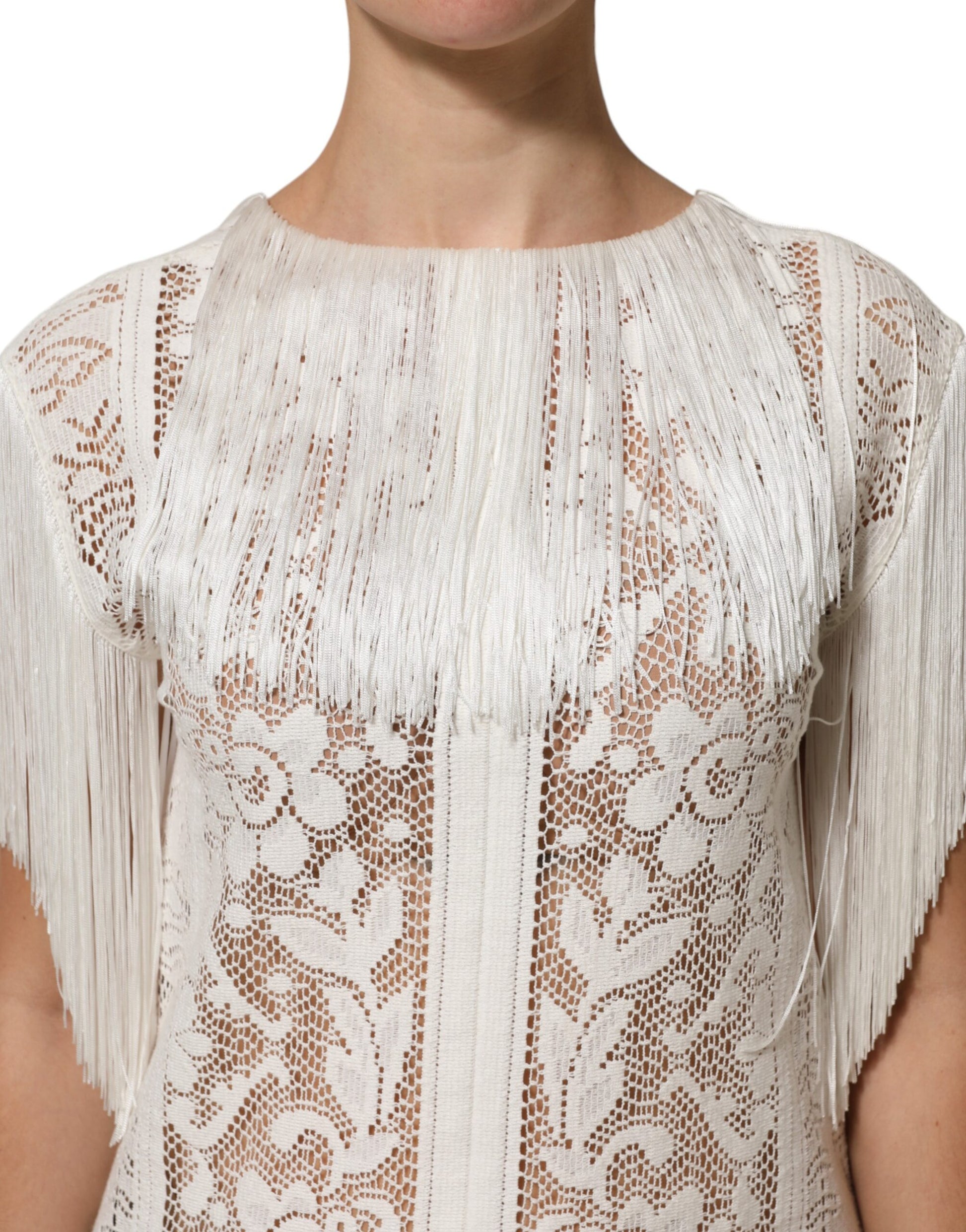 A white lace dress with floral patterns and fringe details on the sleeves