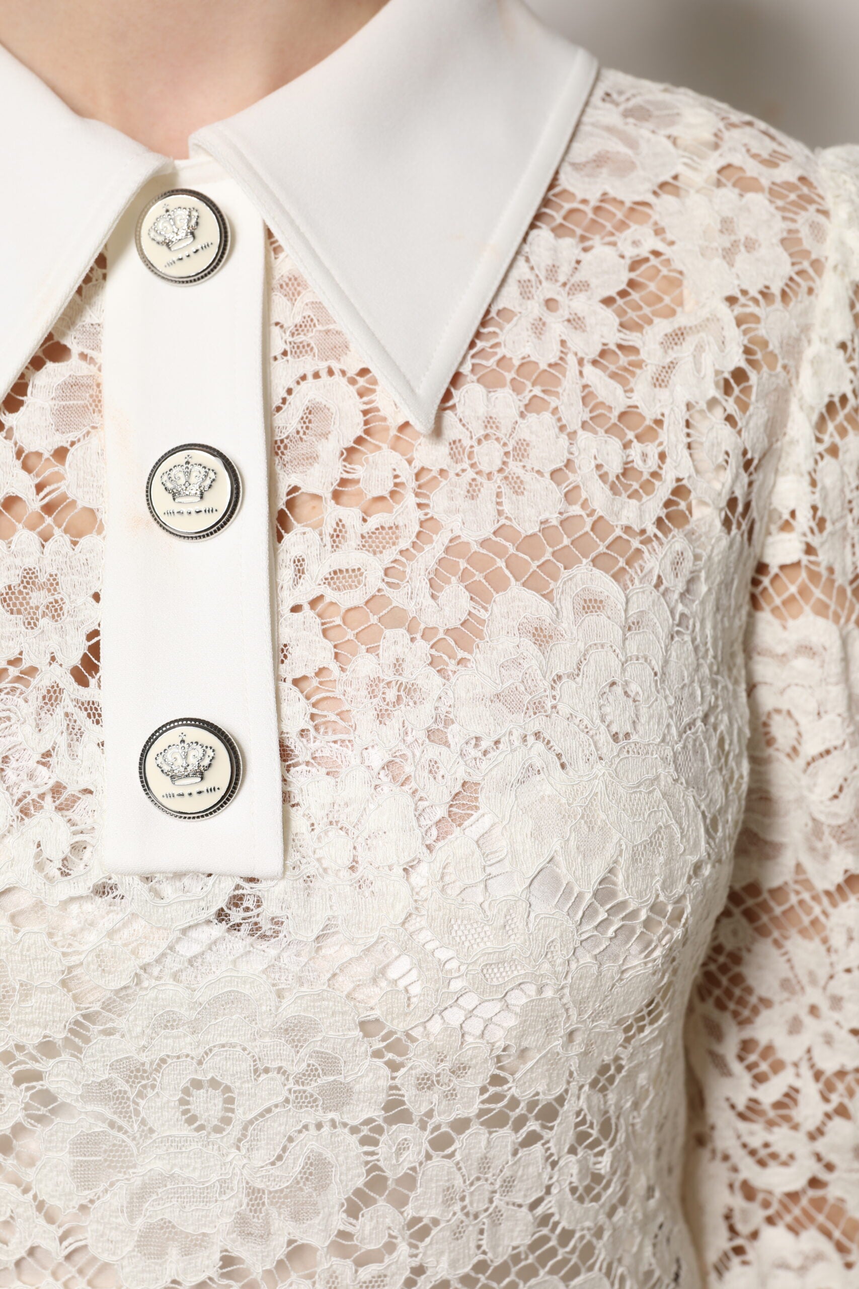 A white lace dress with long sleeves and a high neckline, featuring floral embroidery