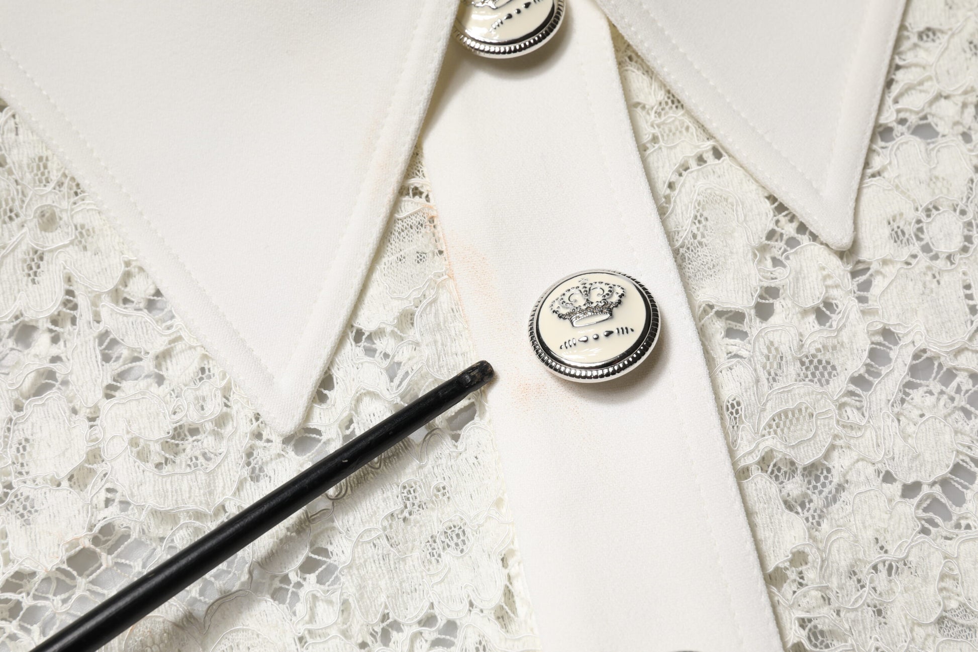 A white floral lace long sleeve dress with a black belt and matching buttons