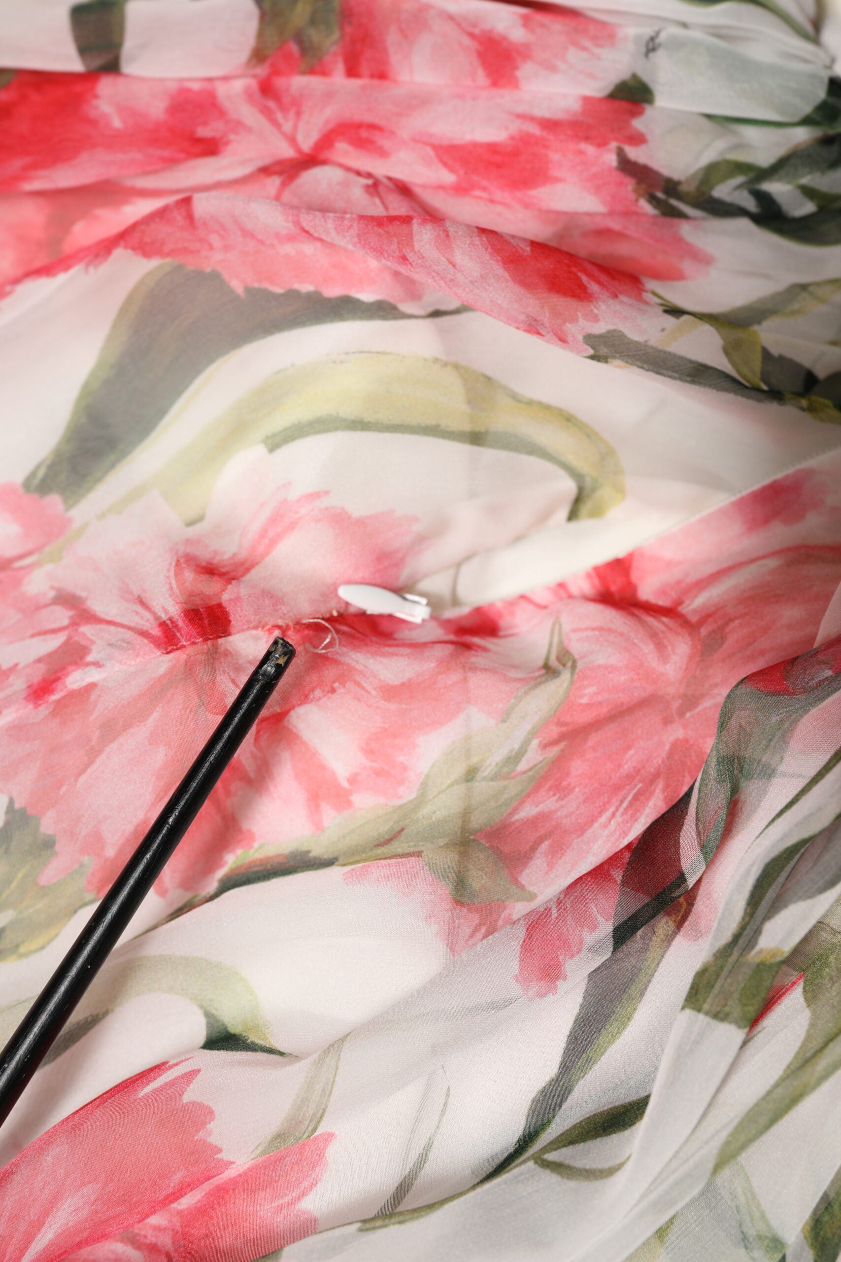 A close-up of a white floral silk halter dress with a maxi length
