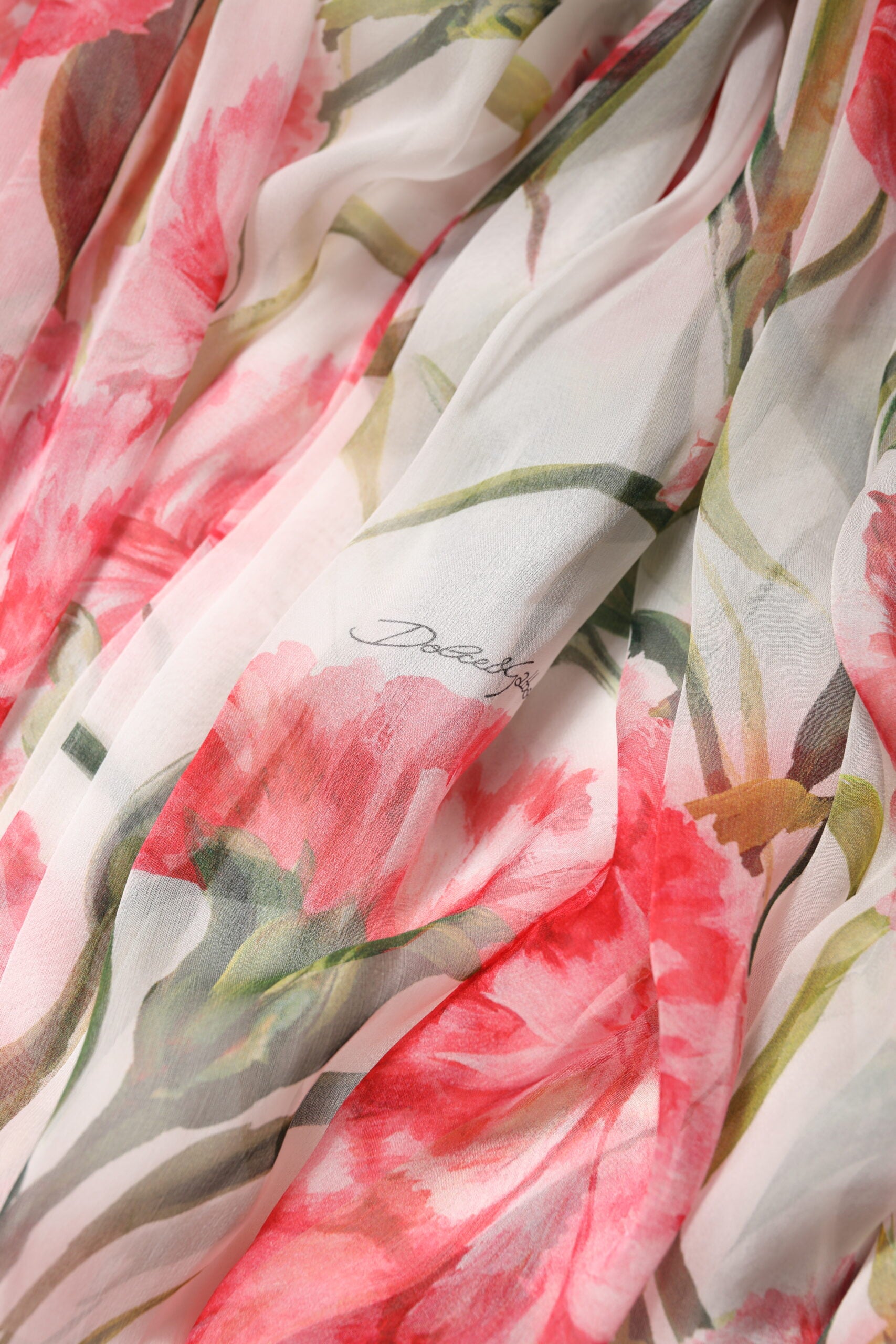 Pink floral patterned scarf with white trim and a small black logo