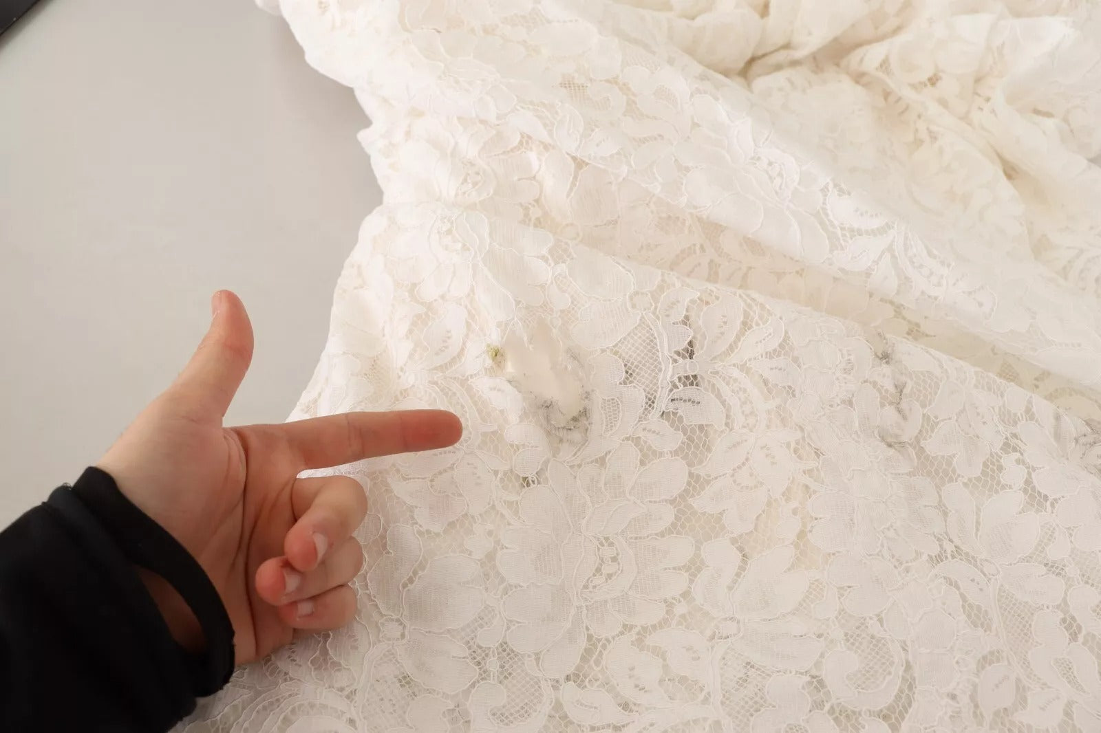 A white lace dress with floral pattern, long sleeves and maxi length