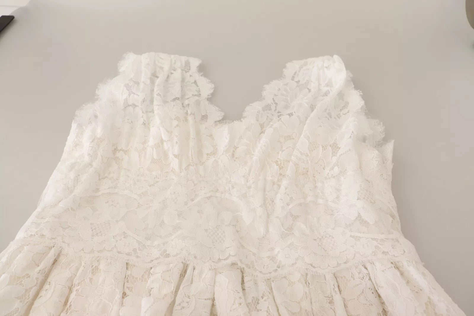 A white lace dress with a long skirt and flower embellishments