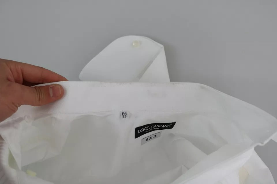 A person's hand holding a white formal tuxedo dress with a gold shirt