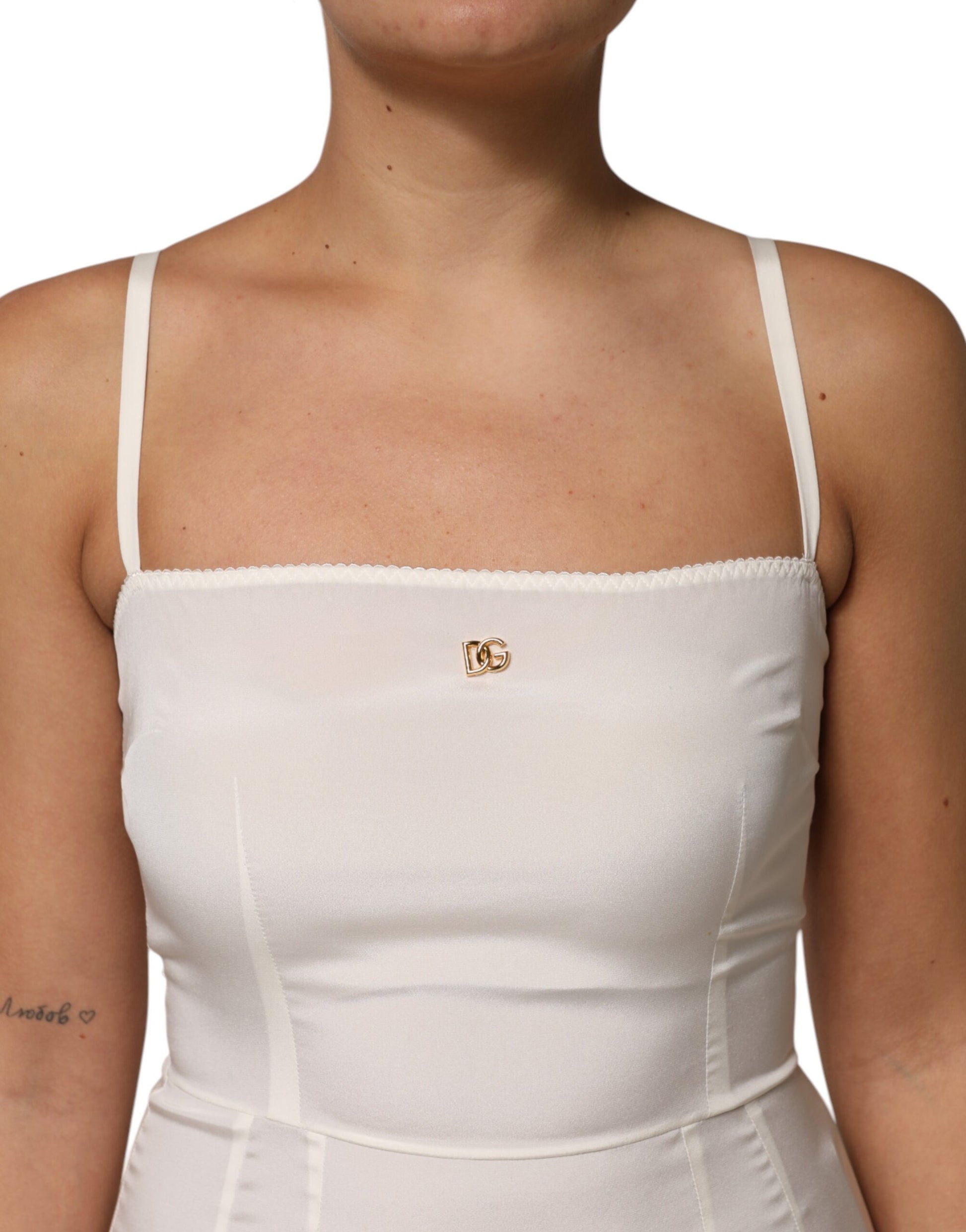 A white full slip dress with a gold logo on the chest