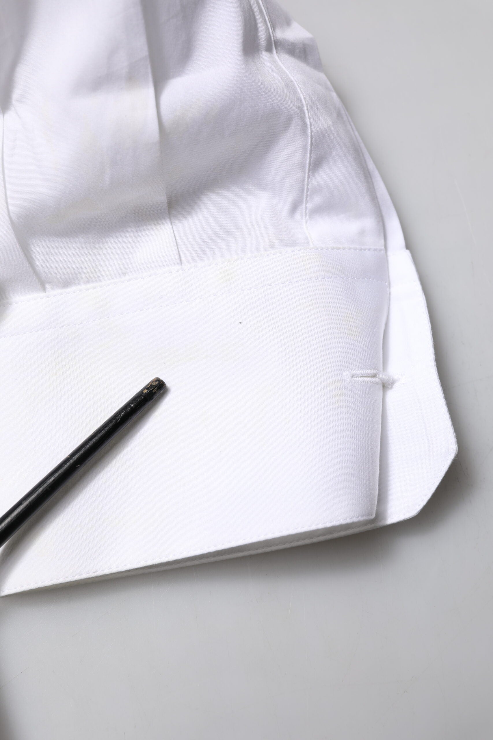 A white dress shirt with a gold bib and black tie clip