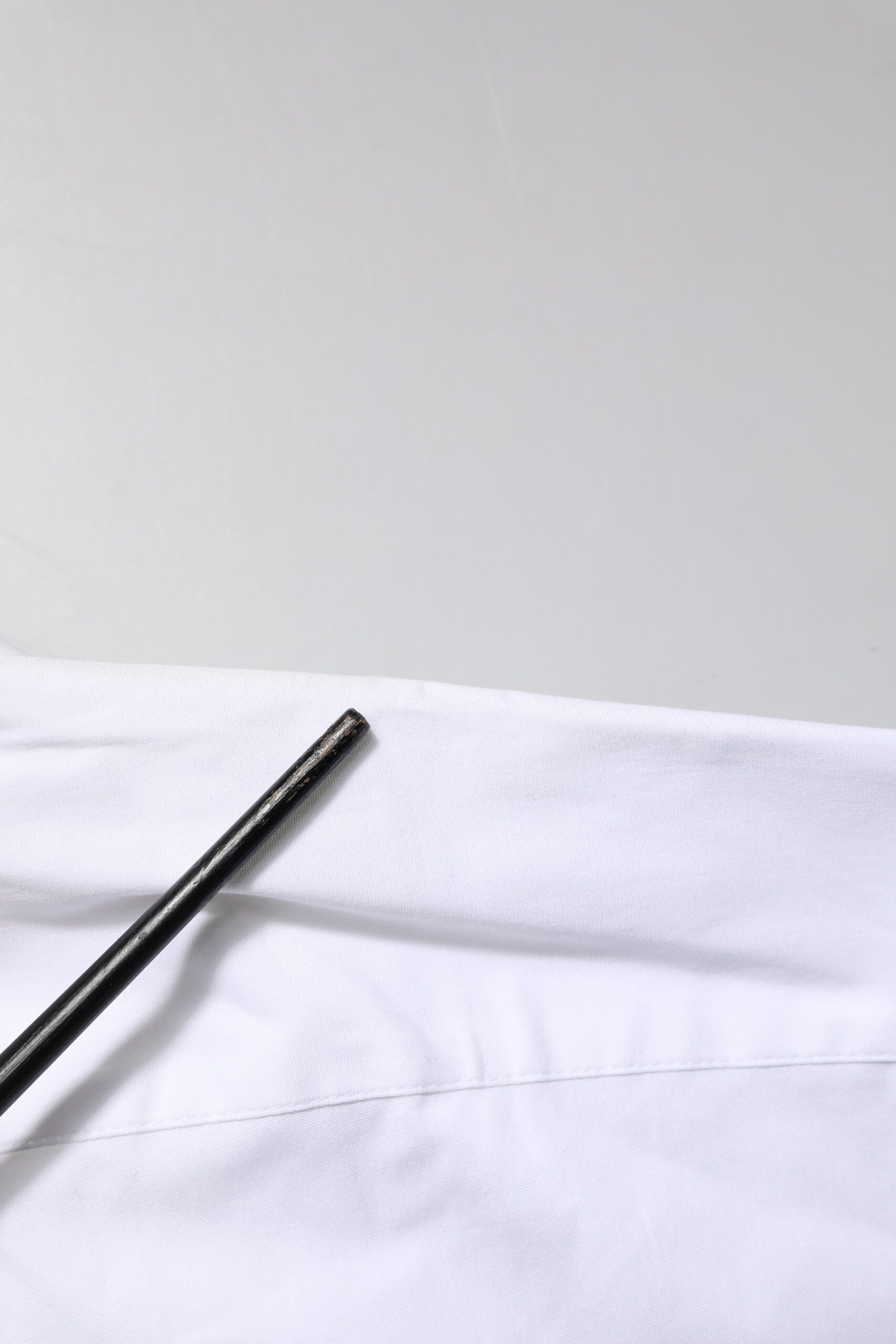 A white collared dress shirt with gold accents, made of cotton