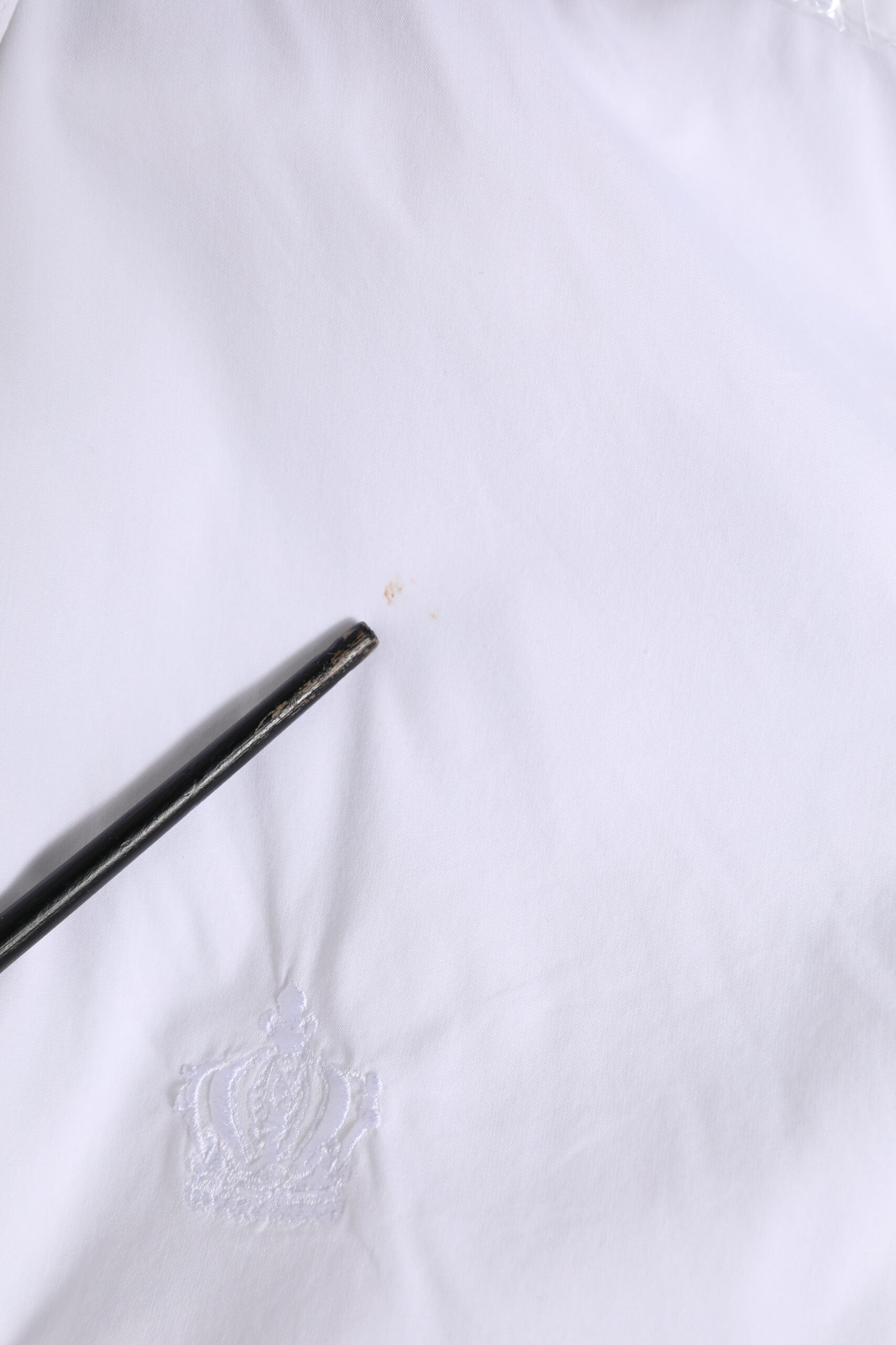 A white cotton formal shirt with a gold emblem on the left chest area