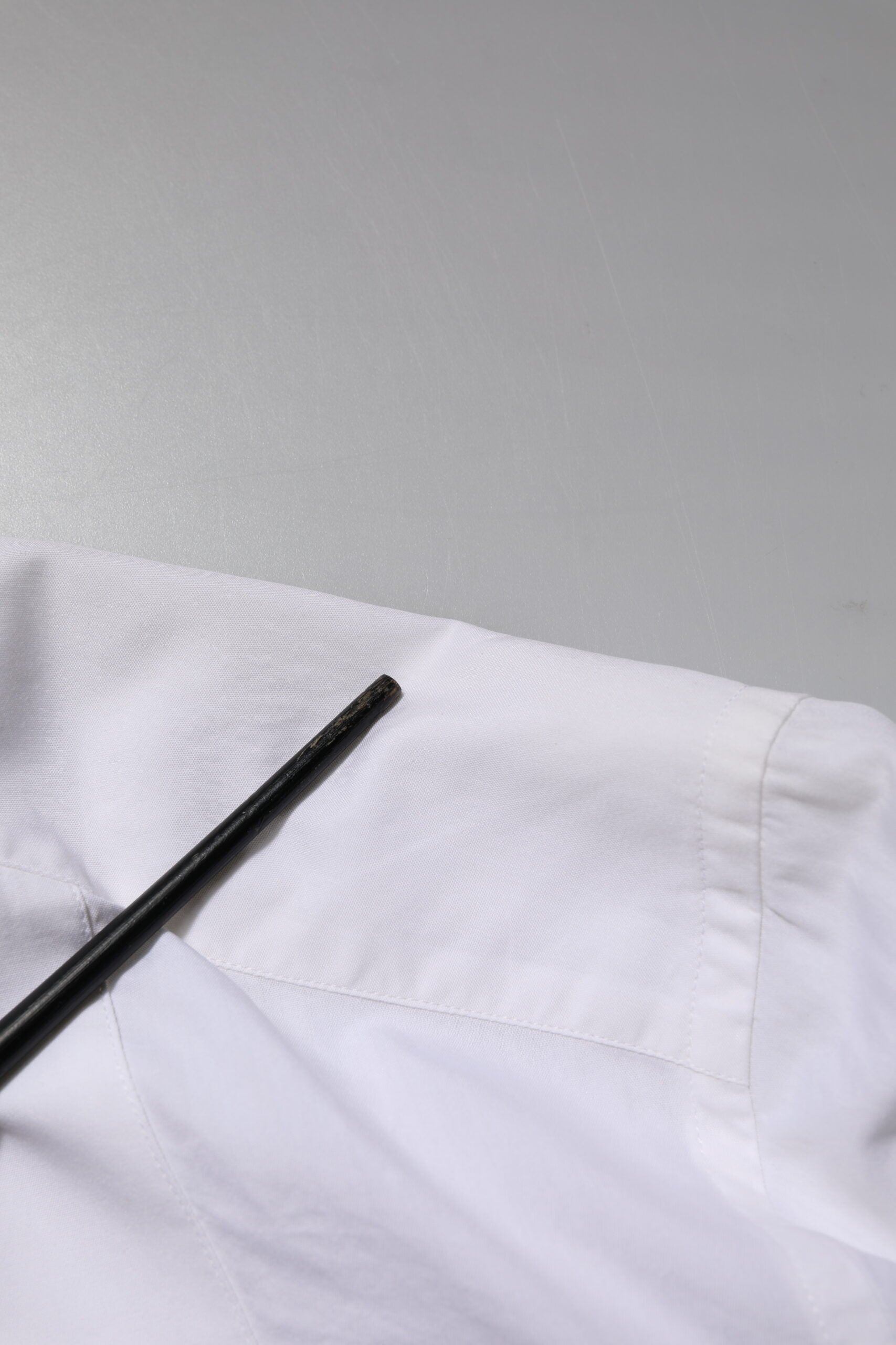 A white cotton poplin dress shirt with gold accents, featuring a black tie