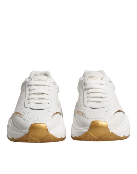 Pair of white gold sneakers with low top, featuring a logo on the side and a strap across the foot