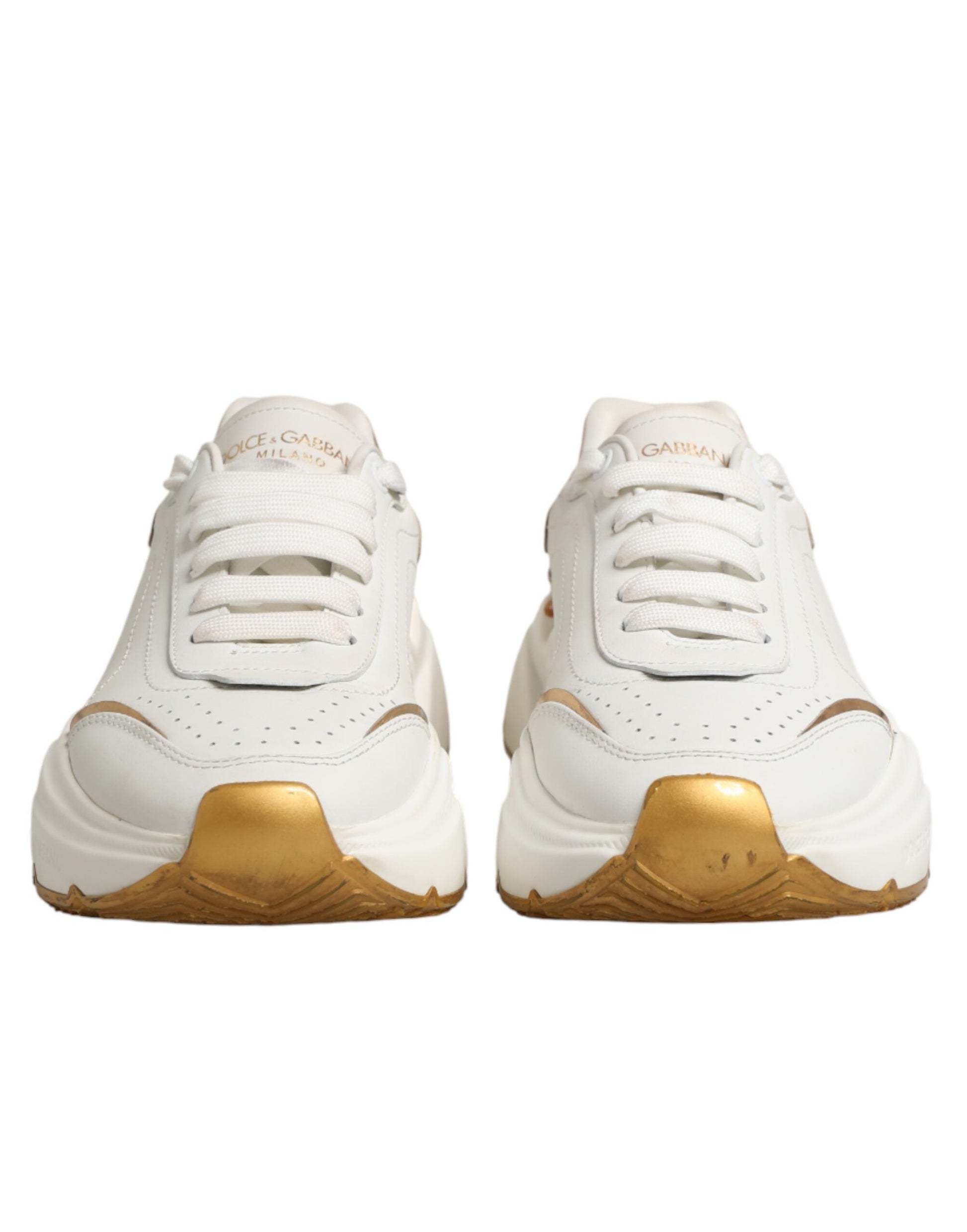 Pair of white gold low top sneakers with laces and a logo on the side