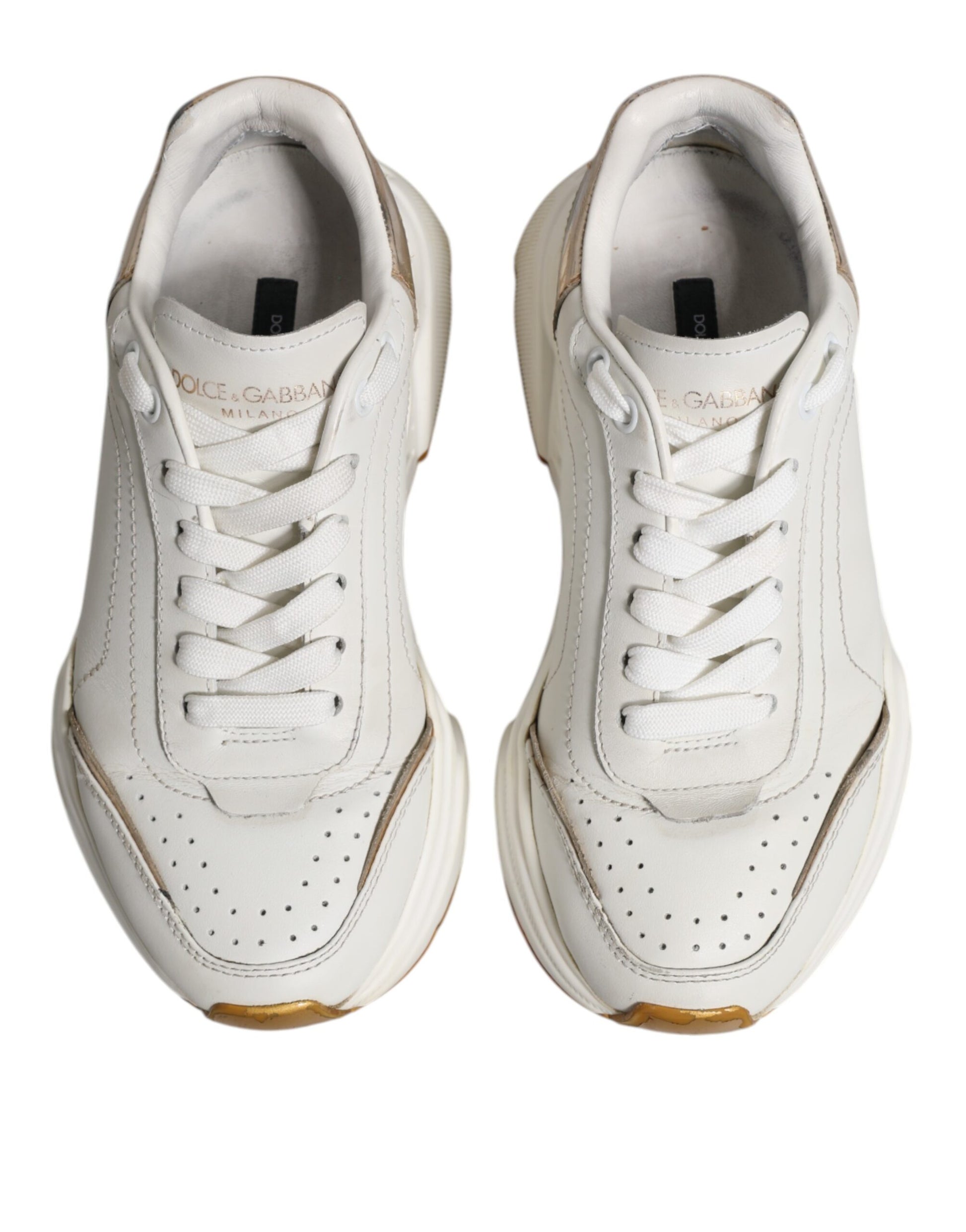 Pair of white gold low top sneakers with black laces and a small logo on the side