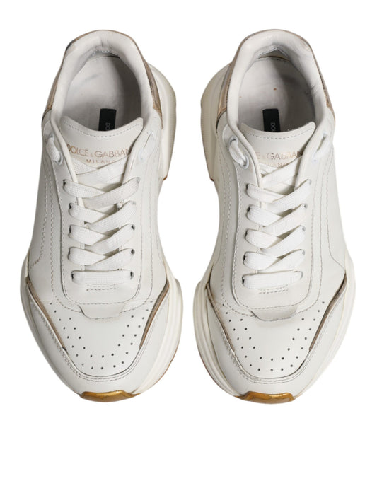 Pair of white gold low top sneakers with black laces and a small logo on the side