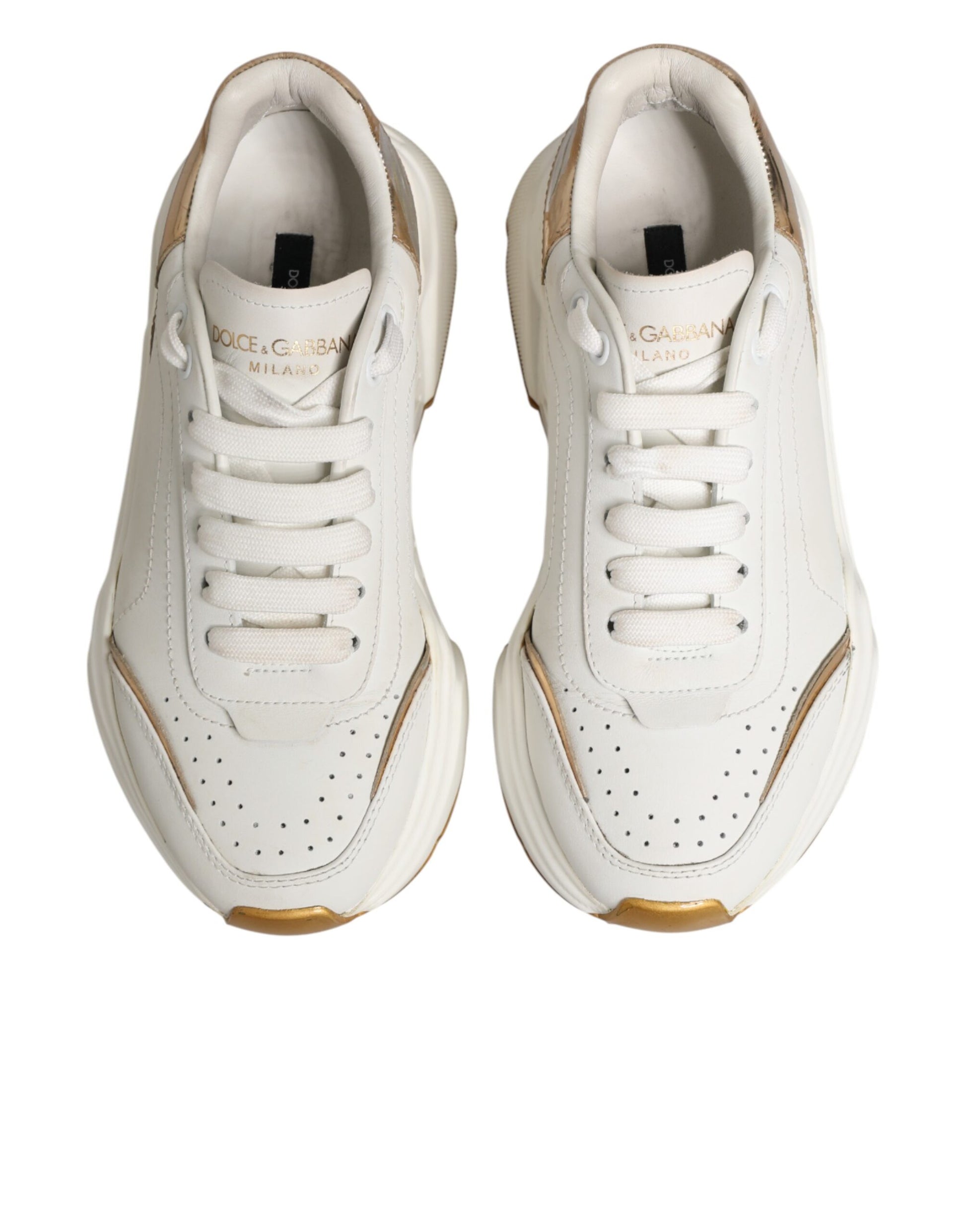 Pair of white gold low top sneakers with black laces and logo on side