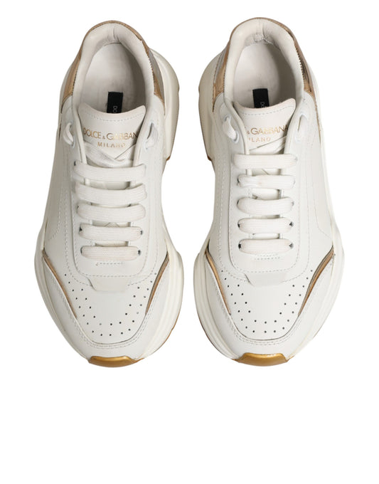 Pair of white gold low top sneakers with black laces and logo on side