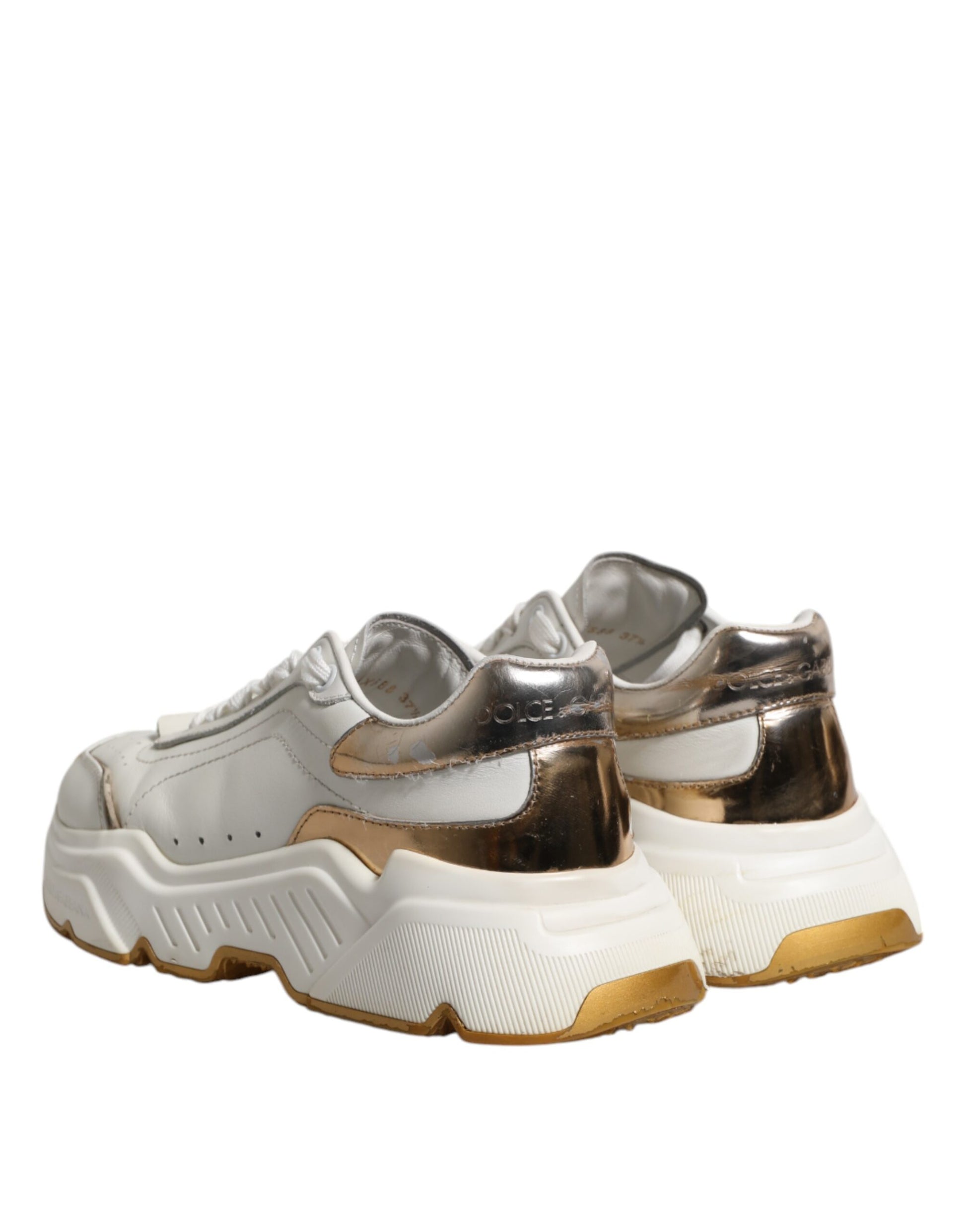 Pair of white gold sneakers with black laces and a chunky sole