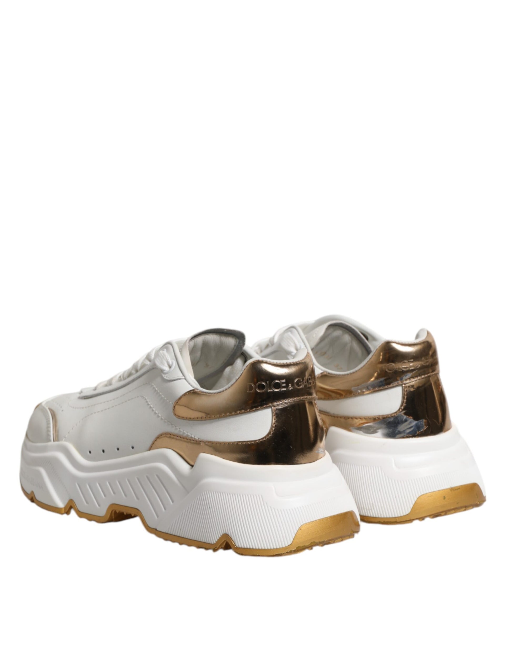 Pair of white gold sneakers with black laces and soles, featuring a low top design