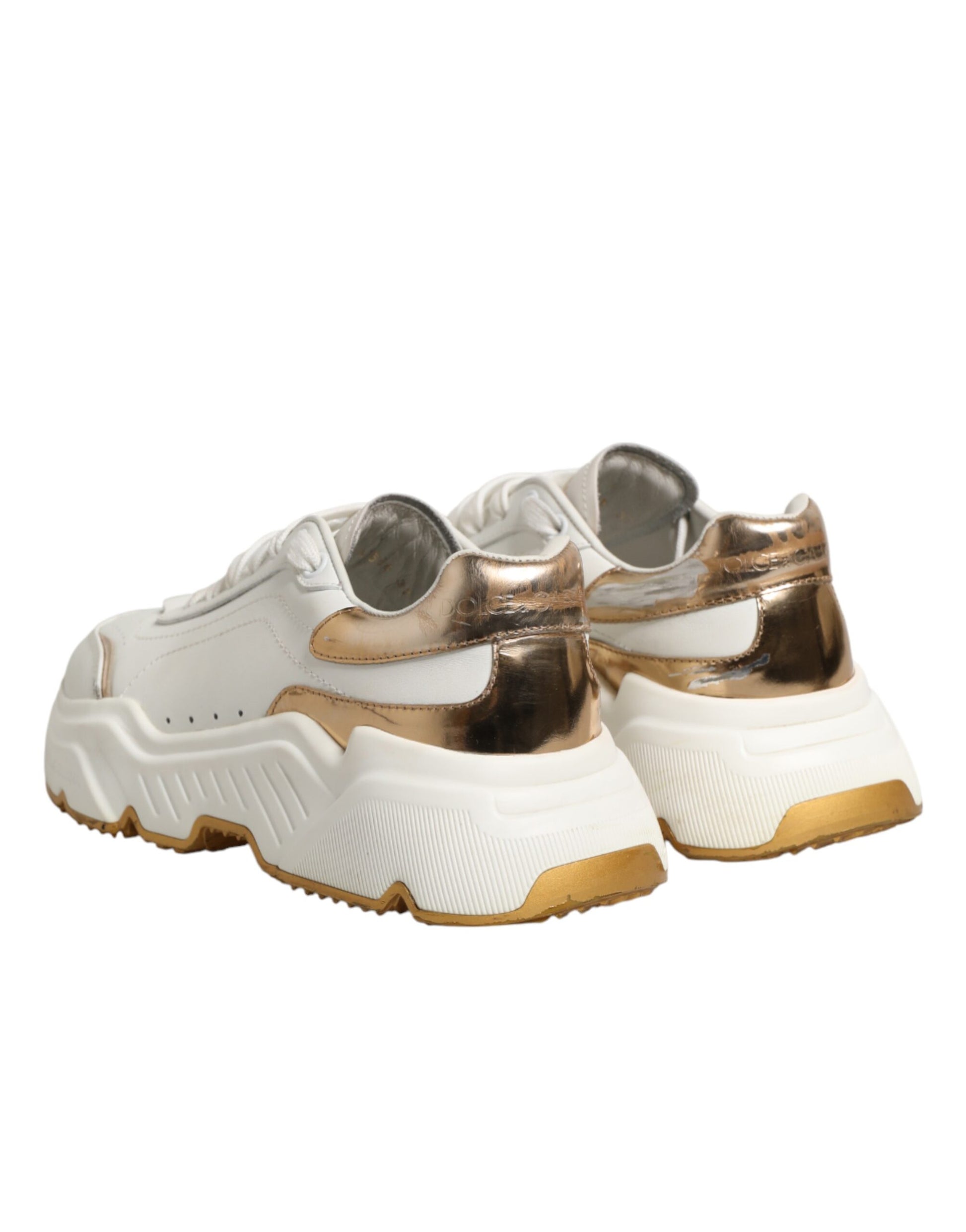Pair of white gold sneakers with black laces and a low top design, featuring a chunky sole