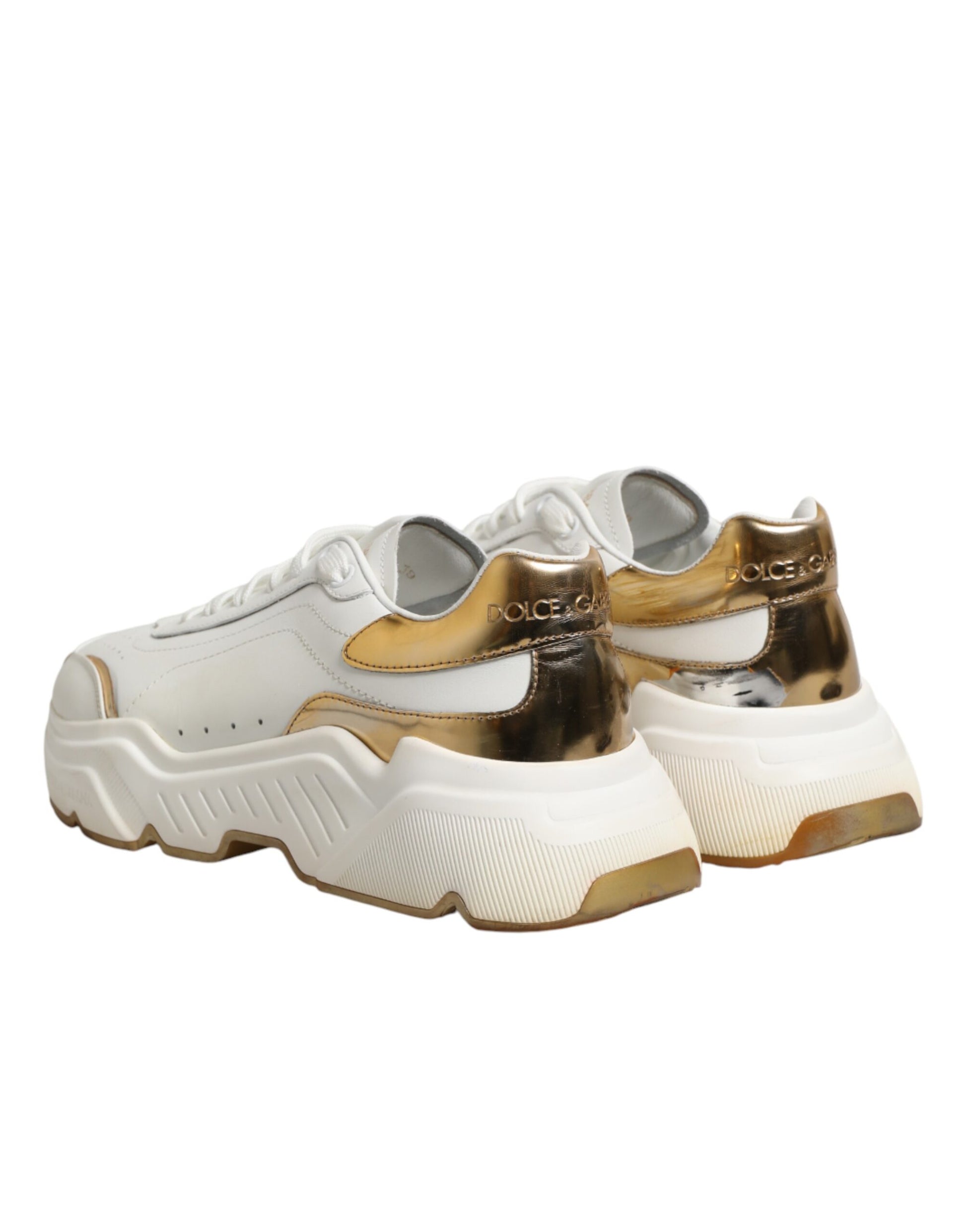Pair of white gold sneakers with black laces and soles, featuring a low top design
