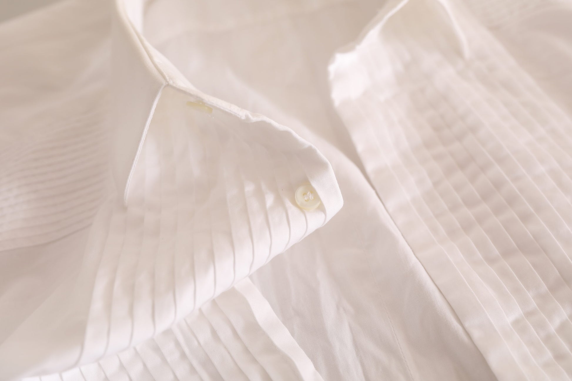 A white cotton tuxedo dress shirt with gold buttons and a collar