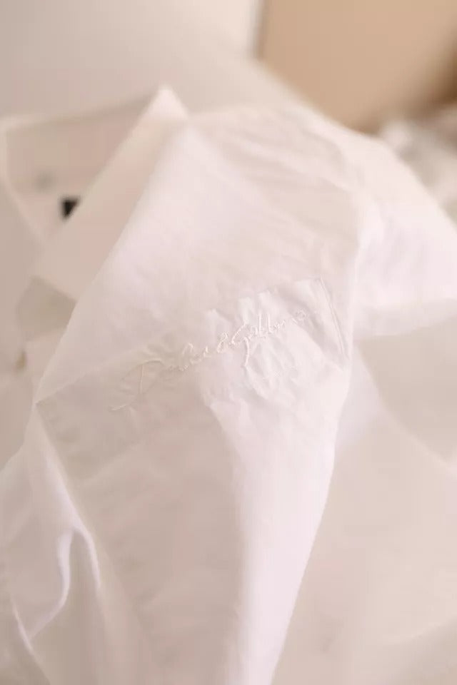 A white cotton tuxedo dress shirt with gold embroidery detail