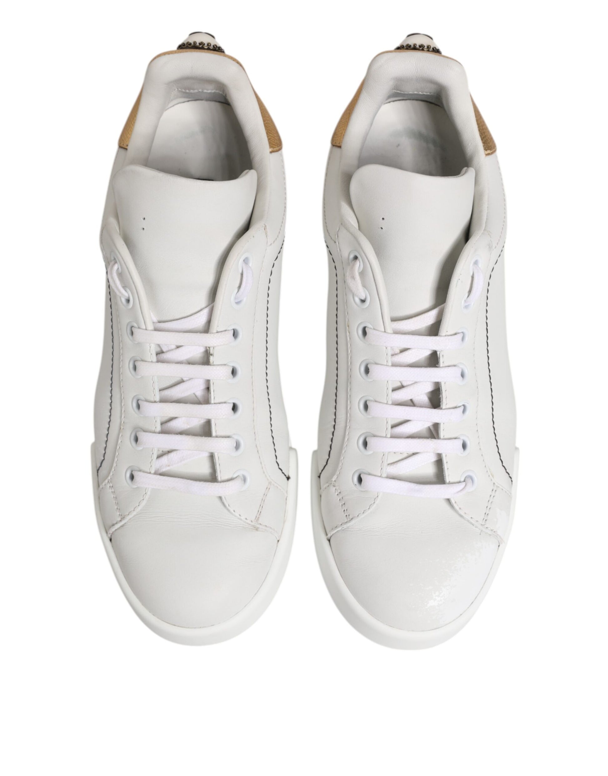 Pair of white gold leather low top sneakers with laces and a logo on the side