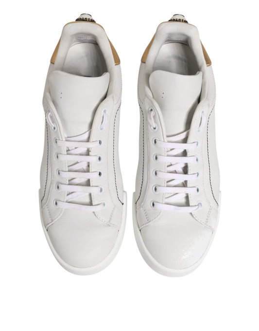Pair of white gold leather low top sneakers with laces and a logo on the side
