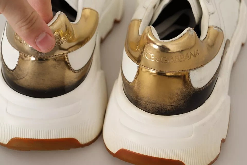 A pair of white gold leather sneakers with a black sole, featuring the brand name "Dolce & Gabbana" on the side