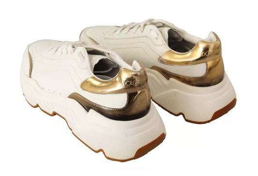 Pair of white gold leather sneakers with laces and a logo on the side