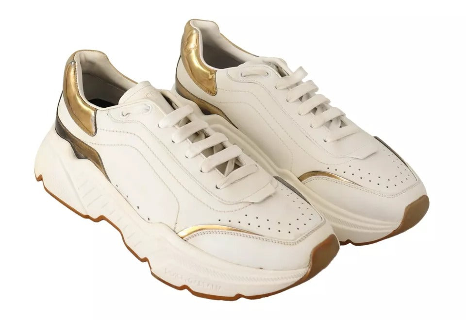 Pair of white gold leather sneakers with laces and a logo on the side
