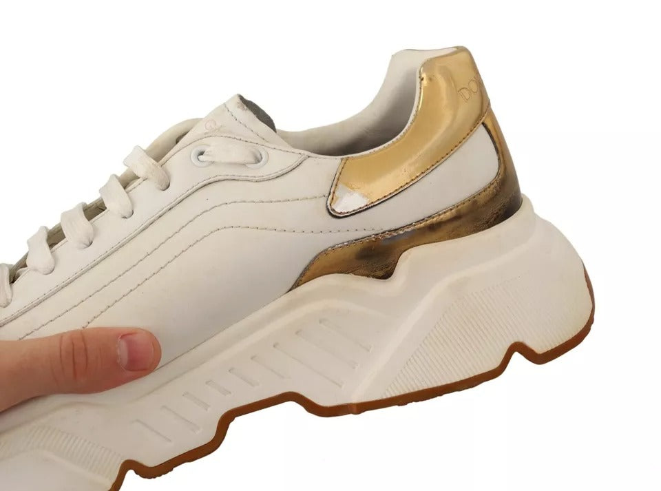 A pair of white gold leather sneakers with a sporty design, featuring a lace-up front and a chunky sole