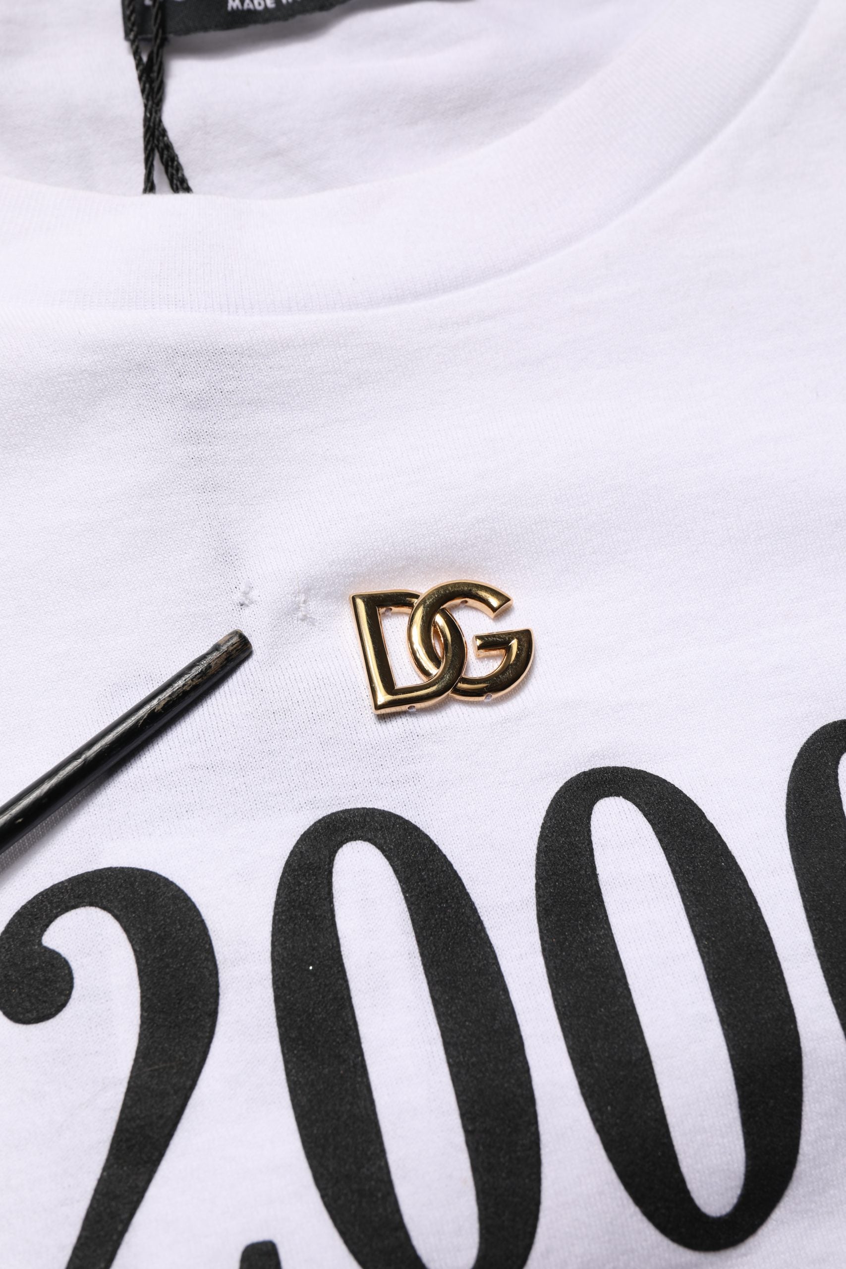 White t-shirt with black lettering and a gold D&G logo on the front