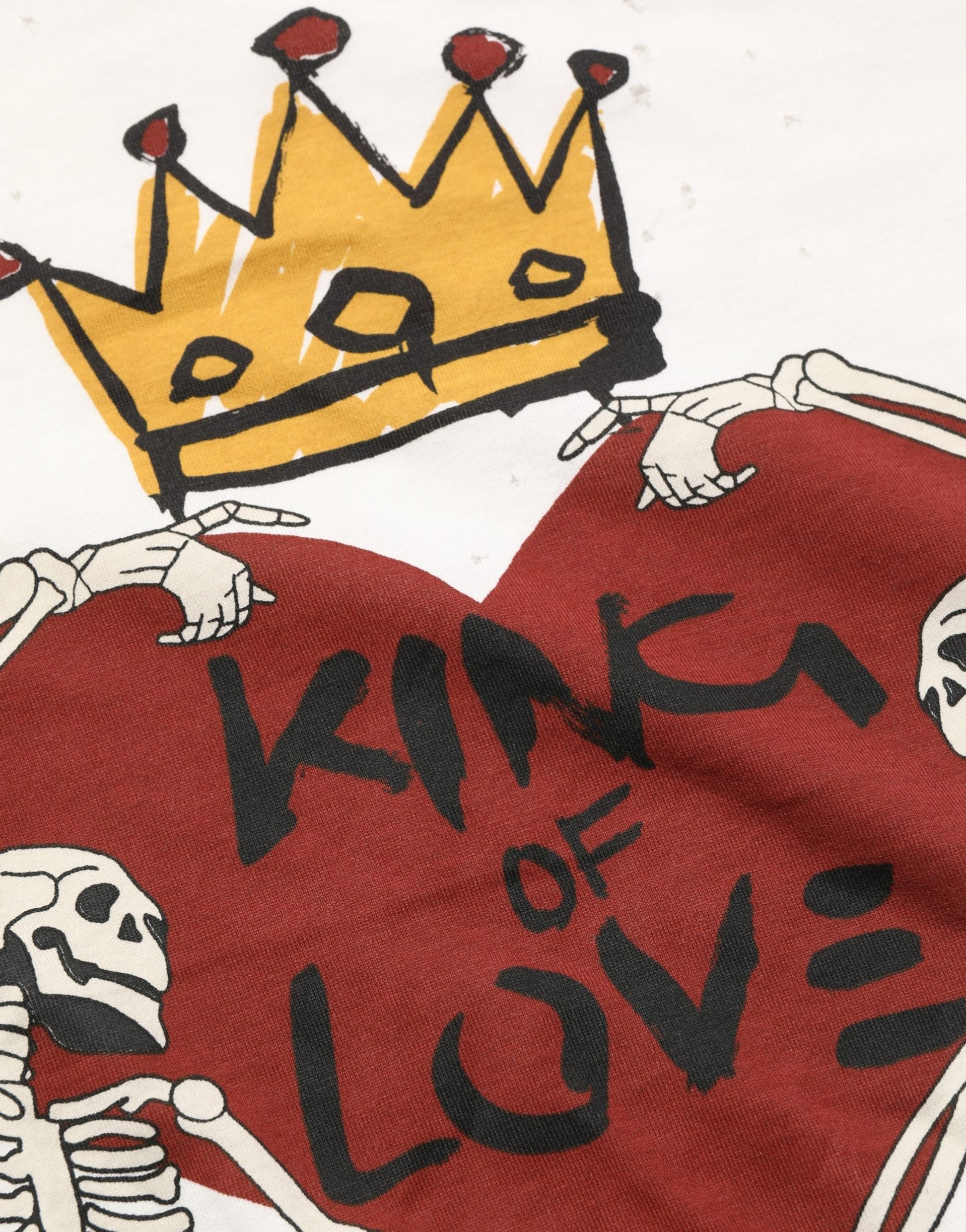 A red t-shirt with a white print of a heart and skeletons, featuring the text "KING OF LOVE" in black