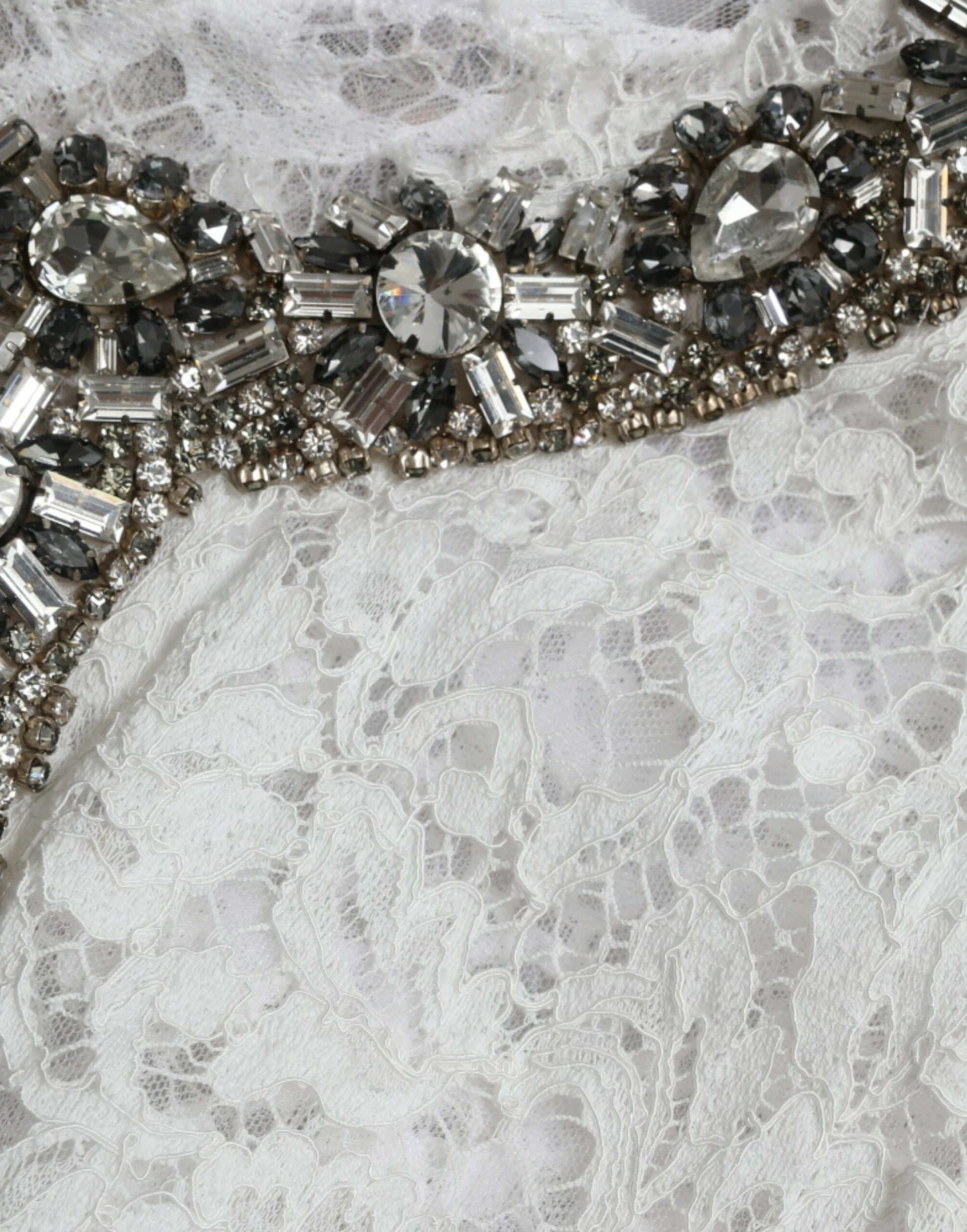 A white lace dress with crystal embellishments on the neckline and waist