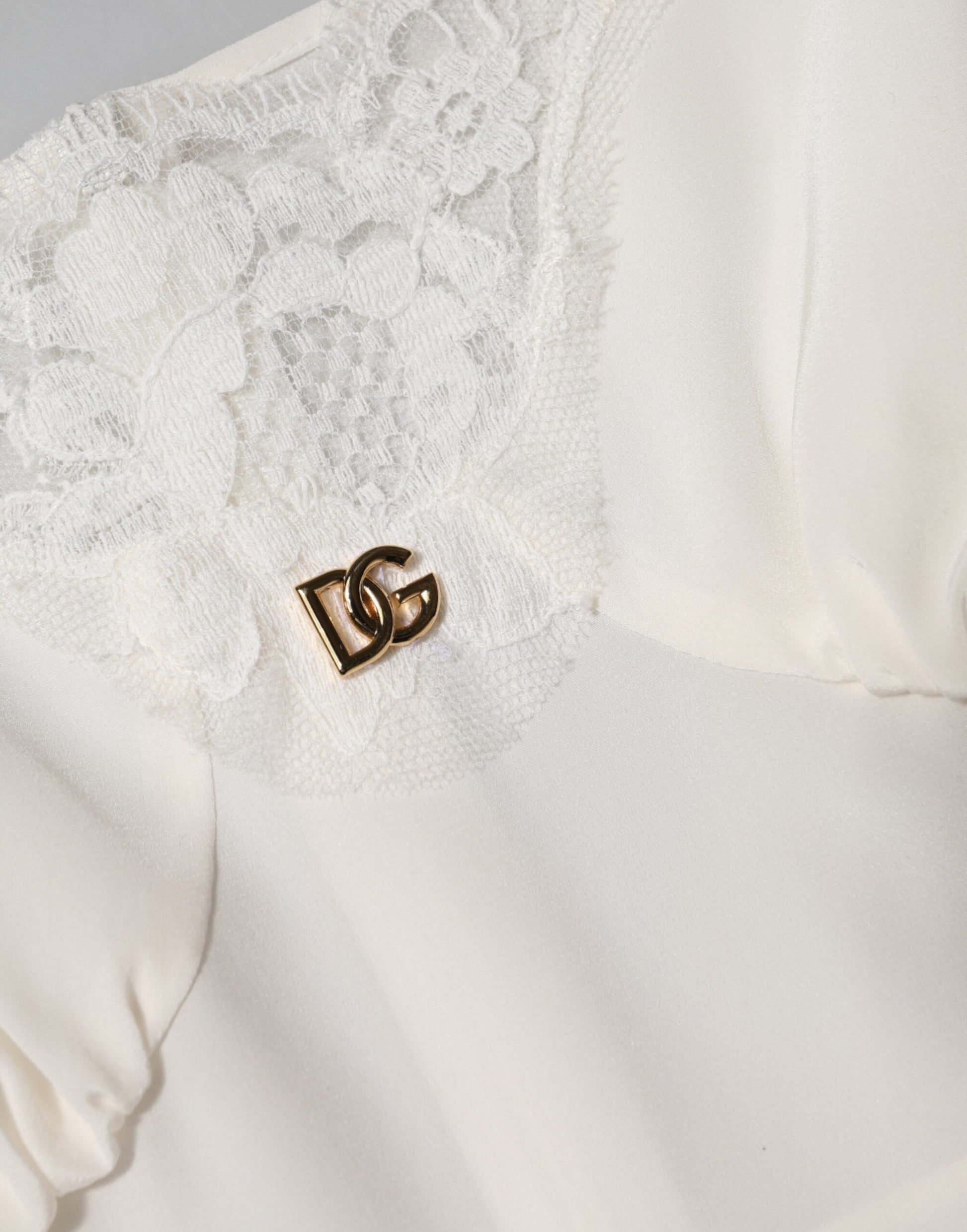 A white lace dress with a gold D&G logo on the chest