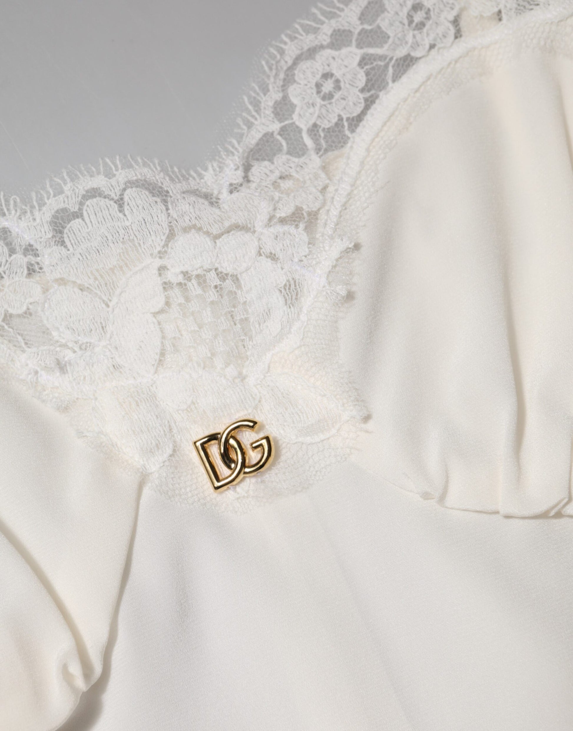 A white lace dress with a gold D&G logo on the shoulder