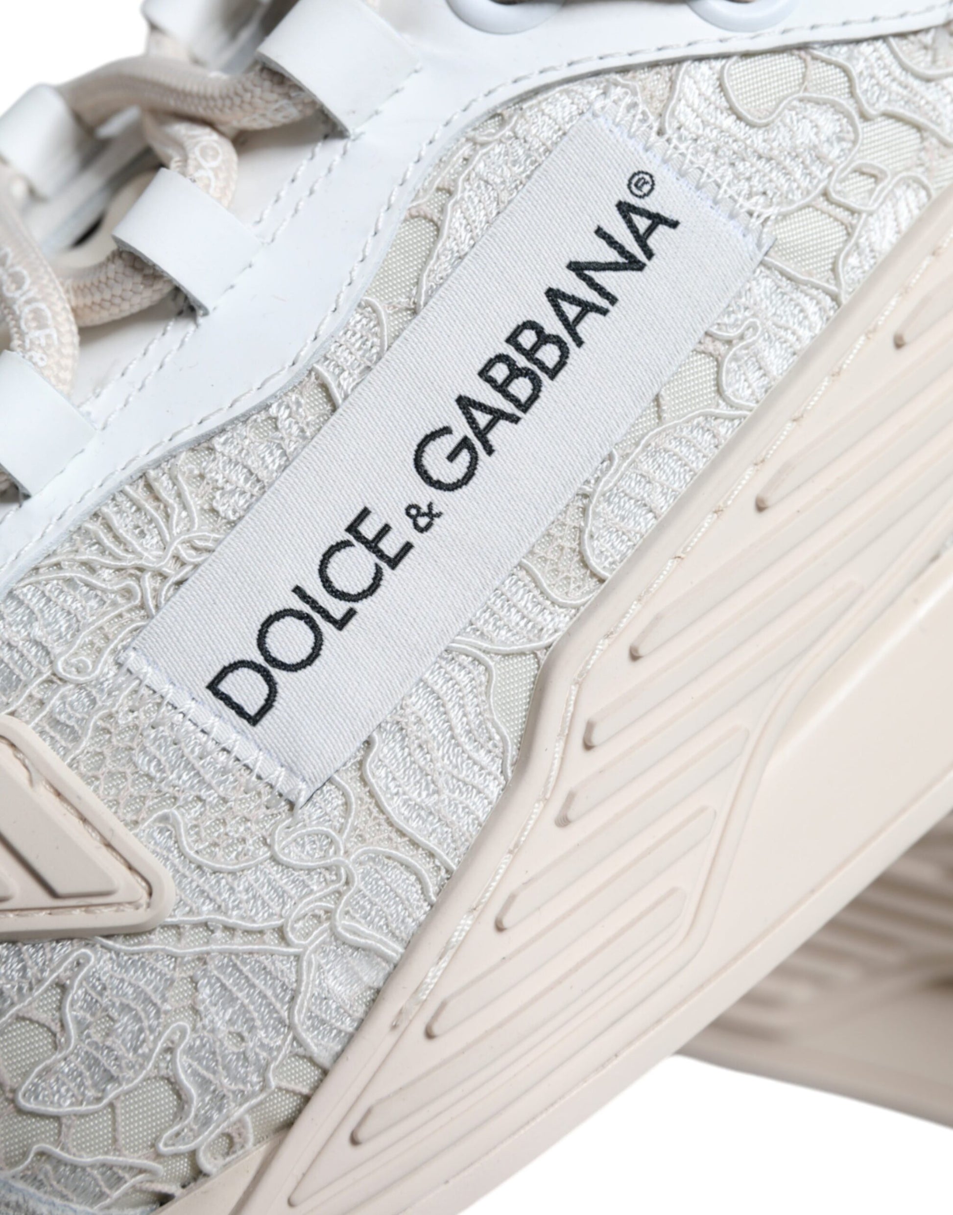 A white lace-up sneaker with a glittery pattern on the side, featuring the Dolce & Gabbana logo