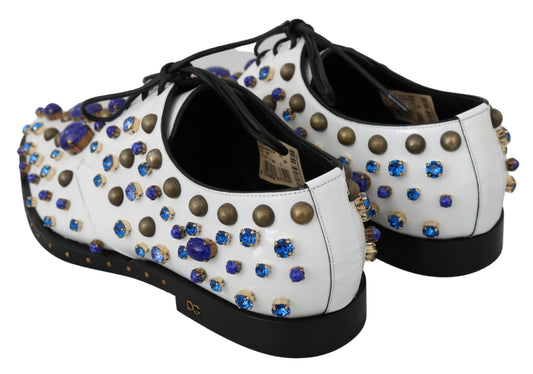 Pair of shoes with white and black upper, gold studs, blue stones, and black soles