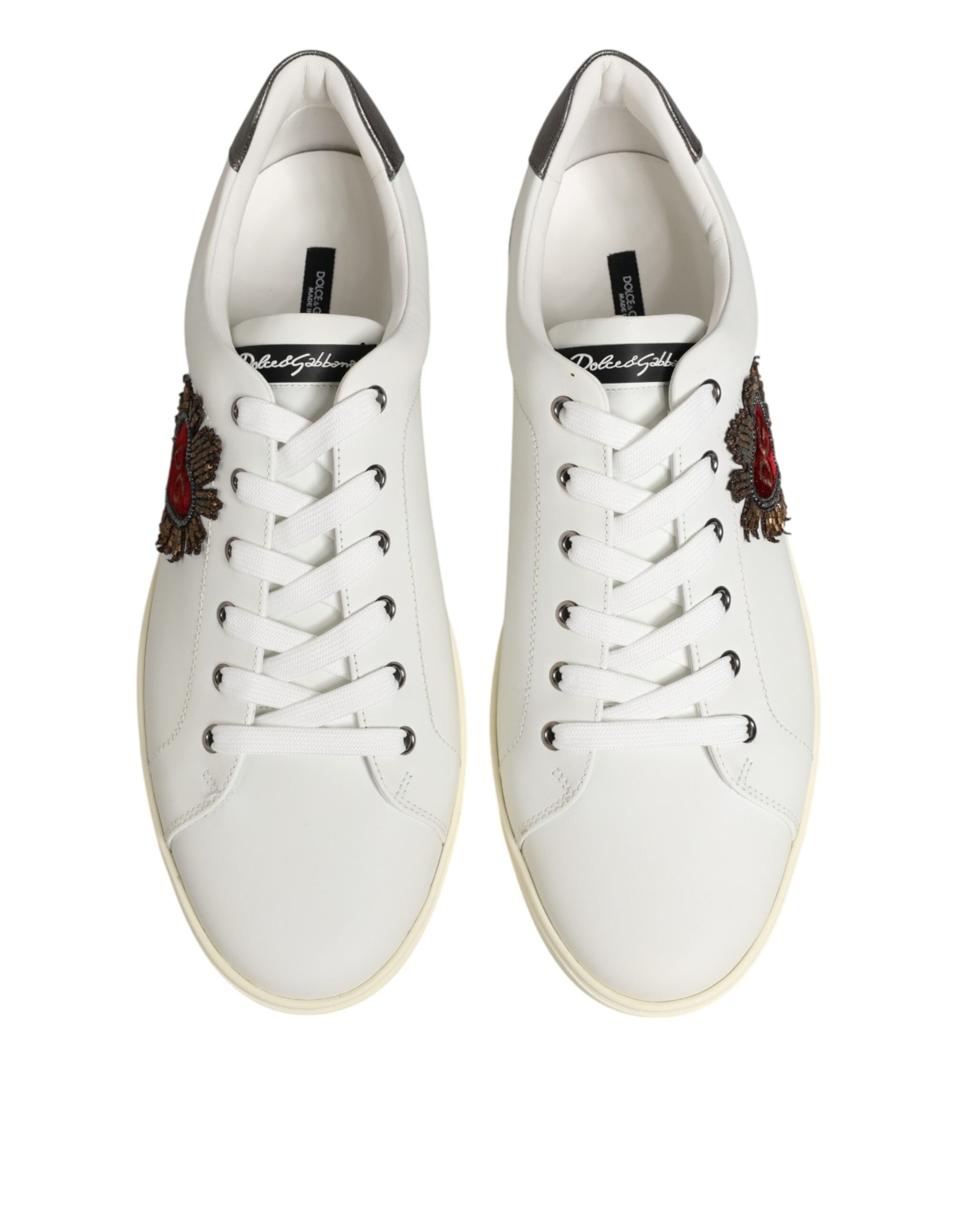 Pair of white leather sneakers with heart embellishment on side, featuring laces and flat soles