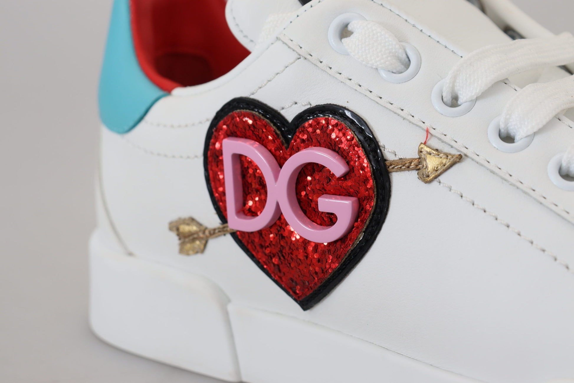 A white leather sneaker with a heart-shaped logo featuring the initials D&G