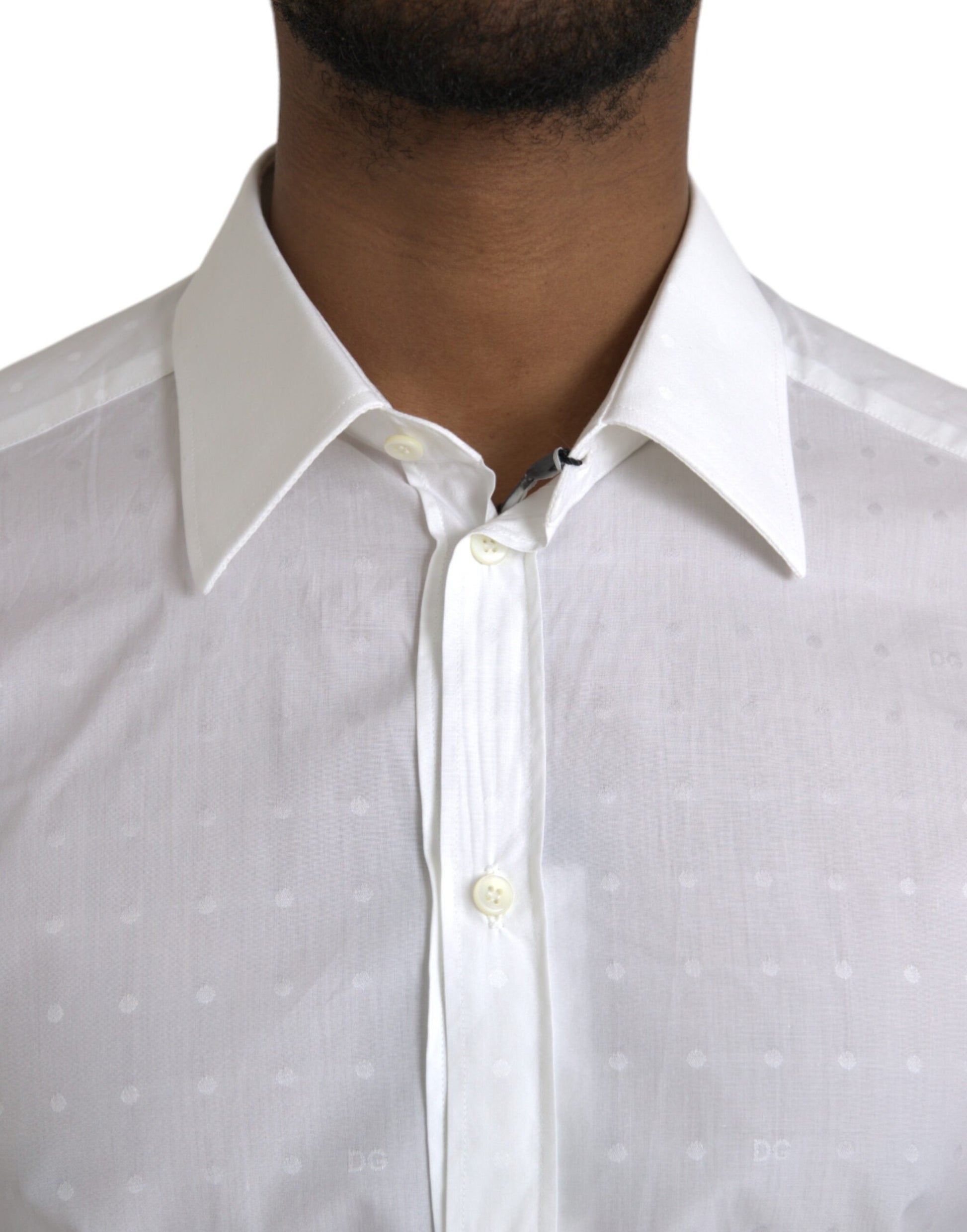 A man wearing a white shirt with a gold logo on the chest