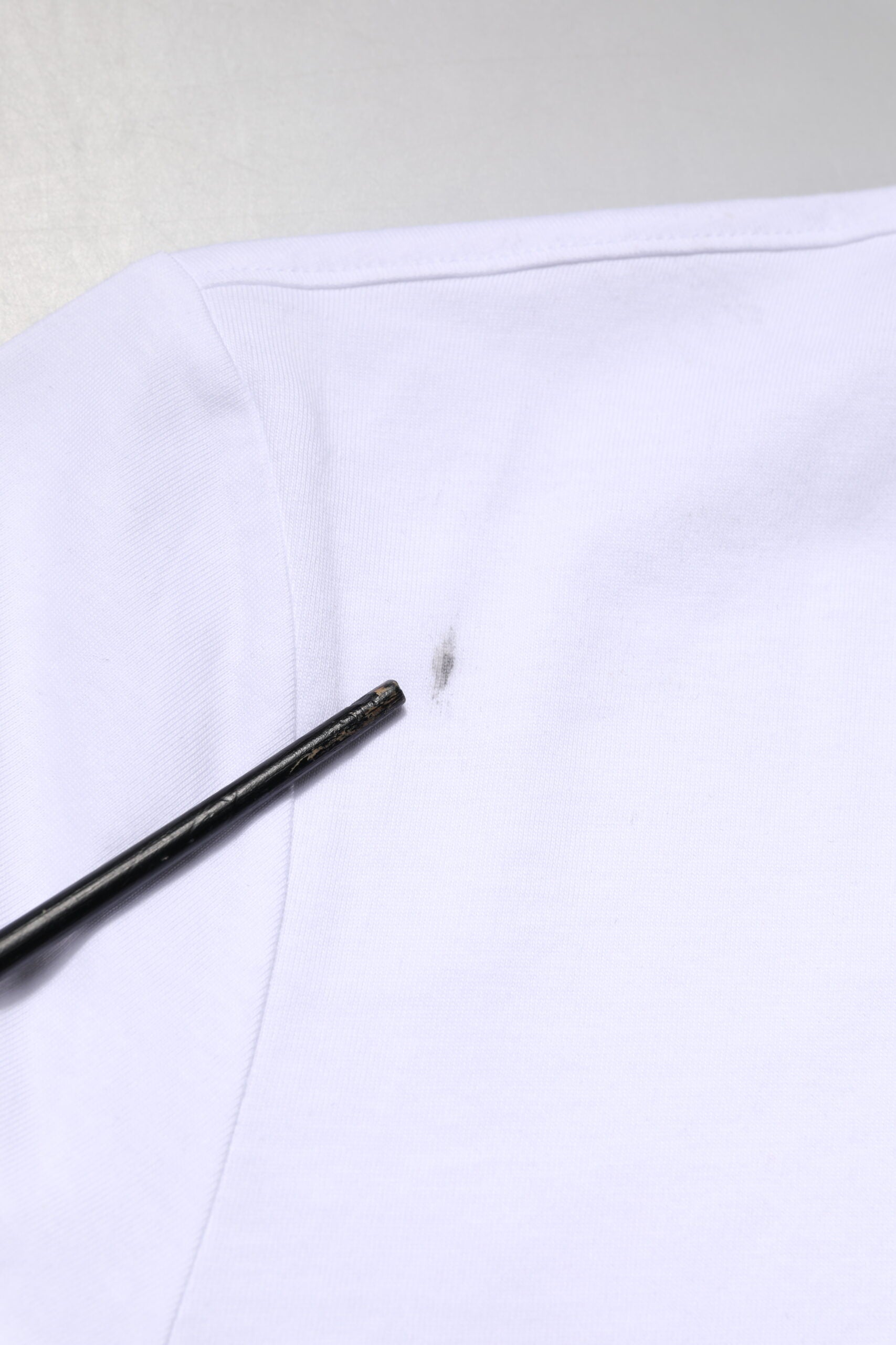 White shirt with a small hole in the shoulder area