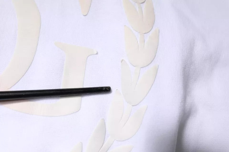 Black pen on white fabric with embroidered laurel wreath