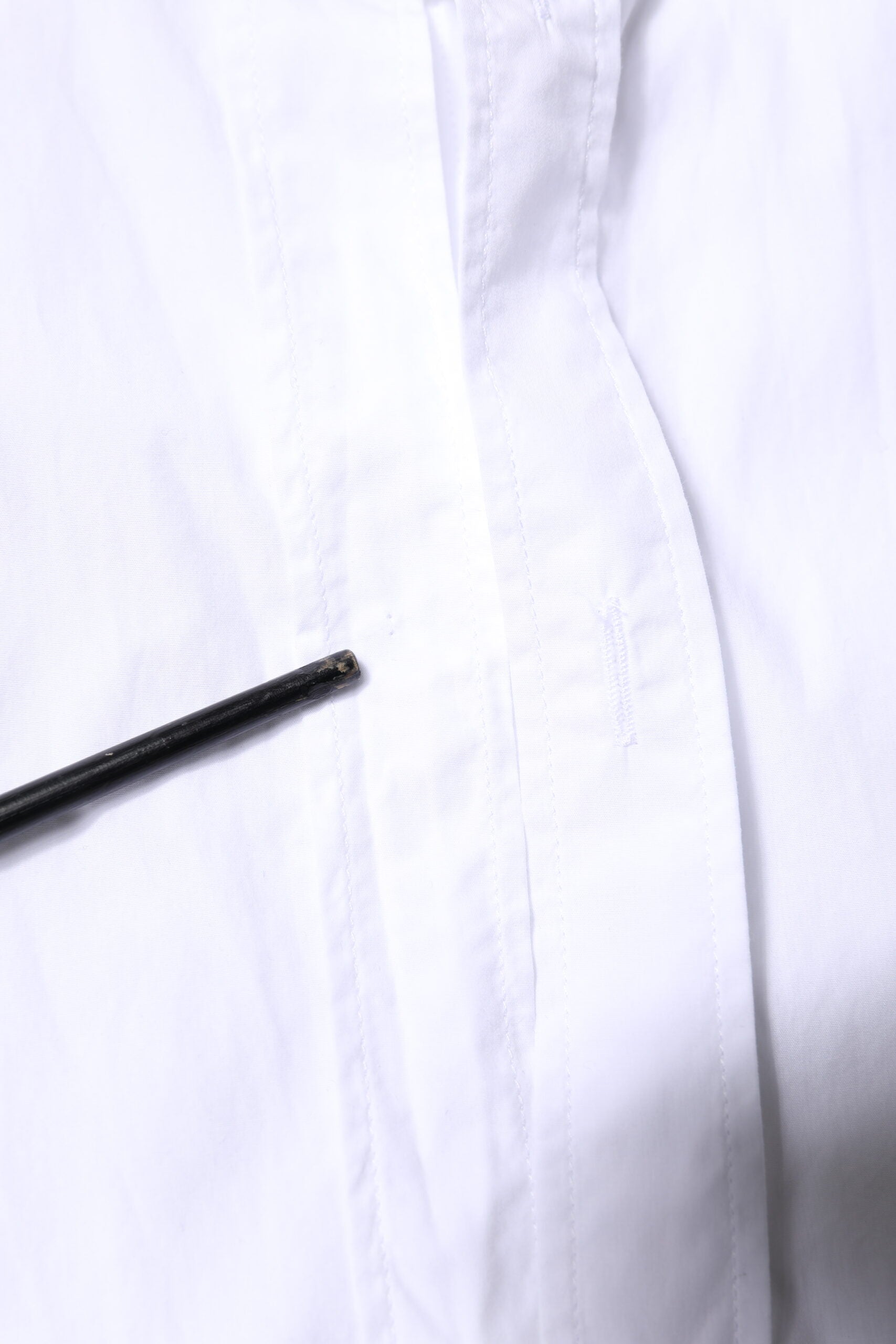 A white men's formal dress shirt with a black tie pin on the left side