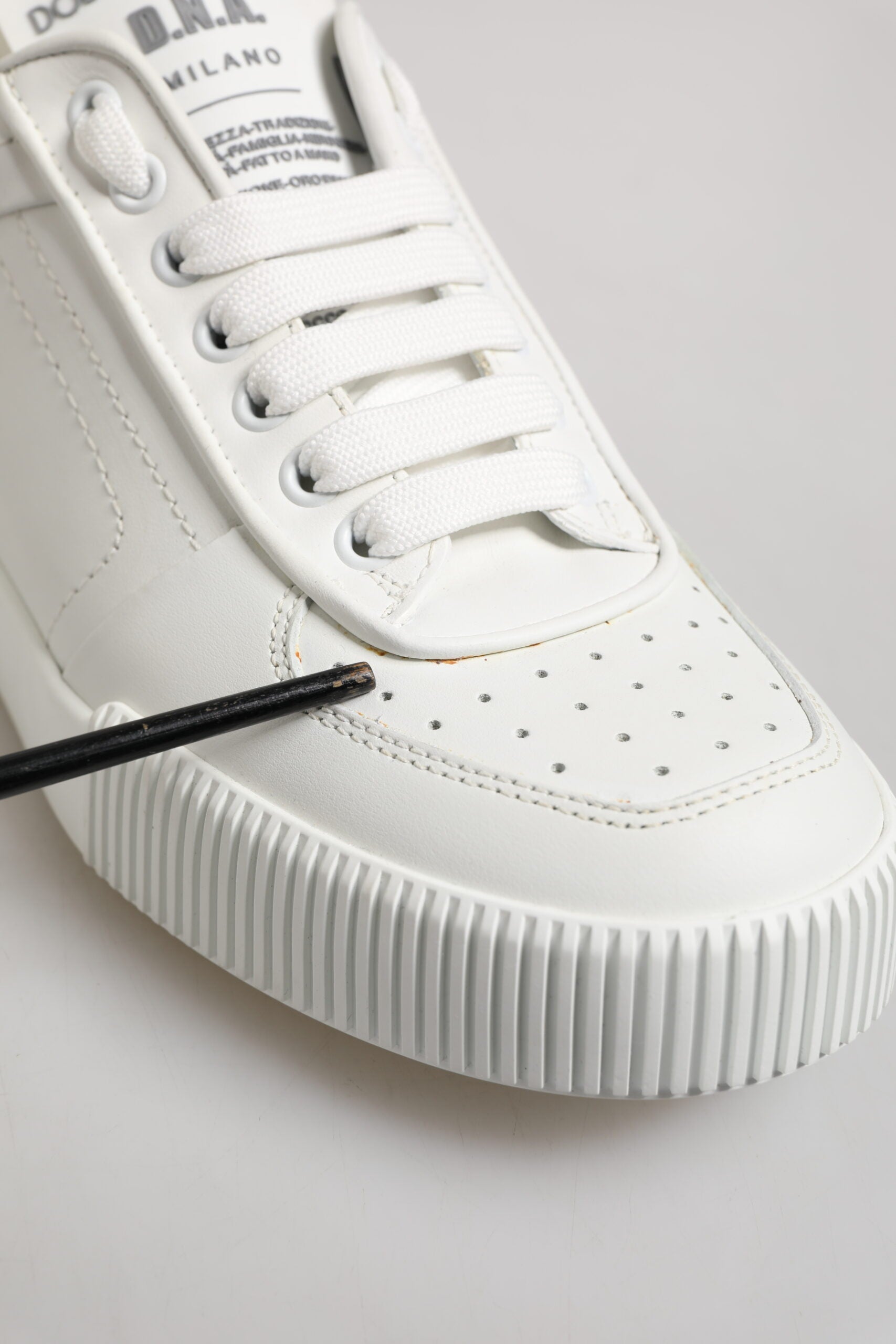 White leather sneakers with black laces, low top, and rubber sole